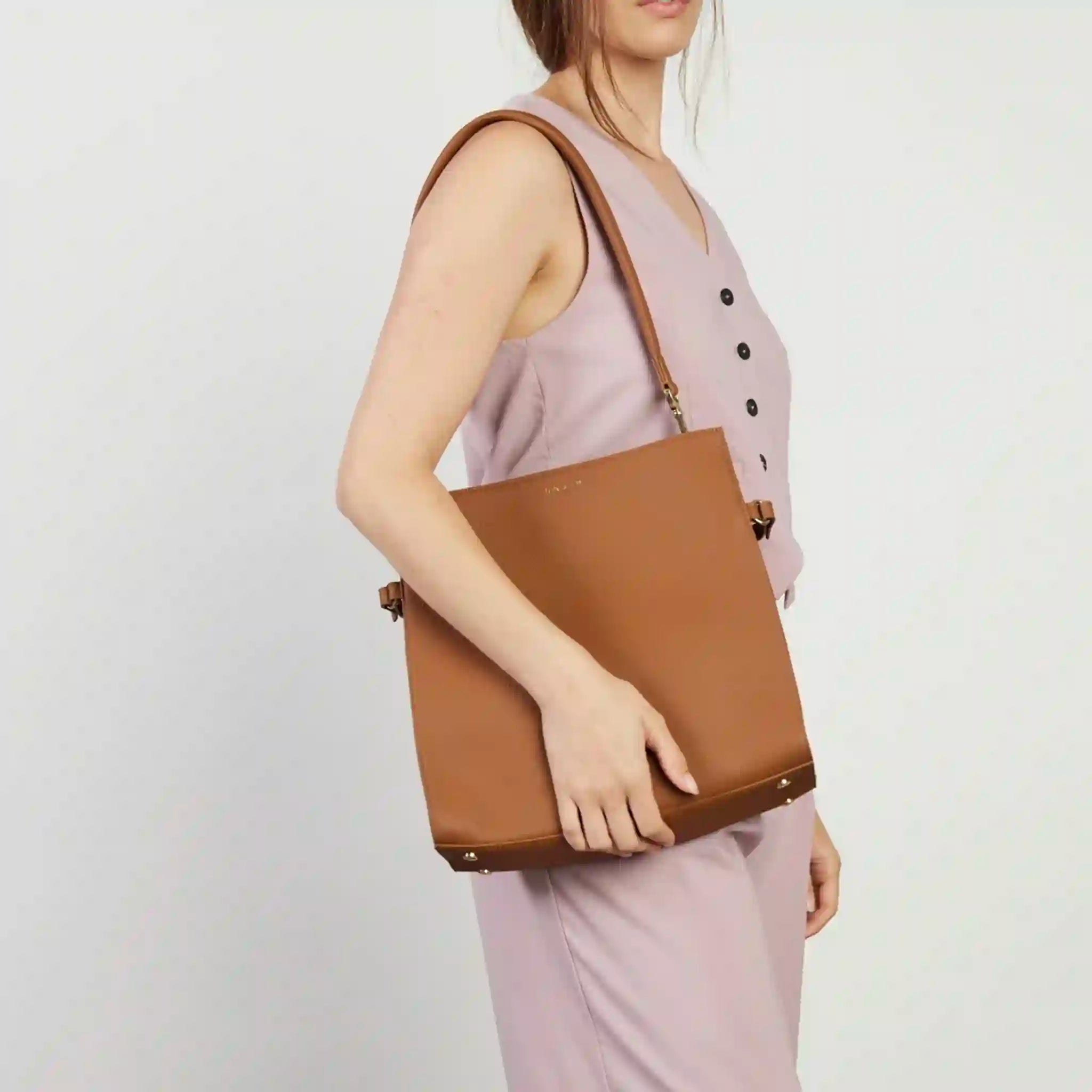 Woman holding a brown tote bag against a plain background