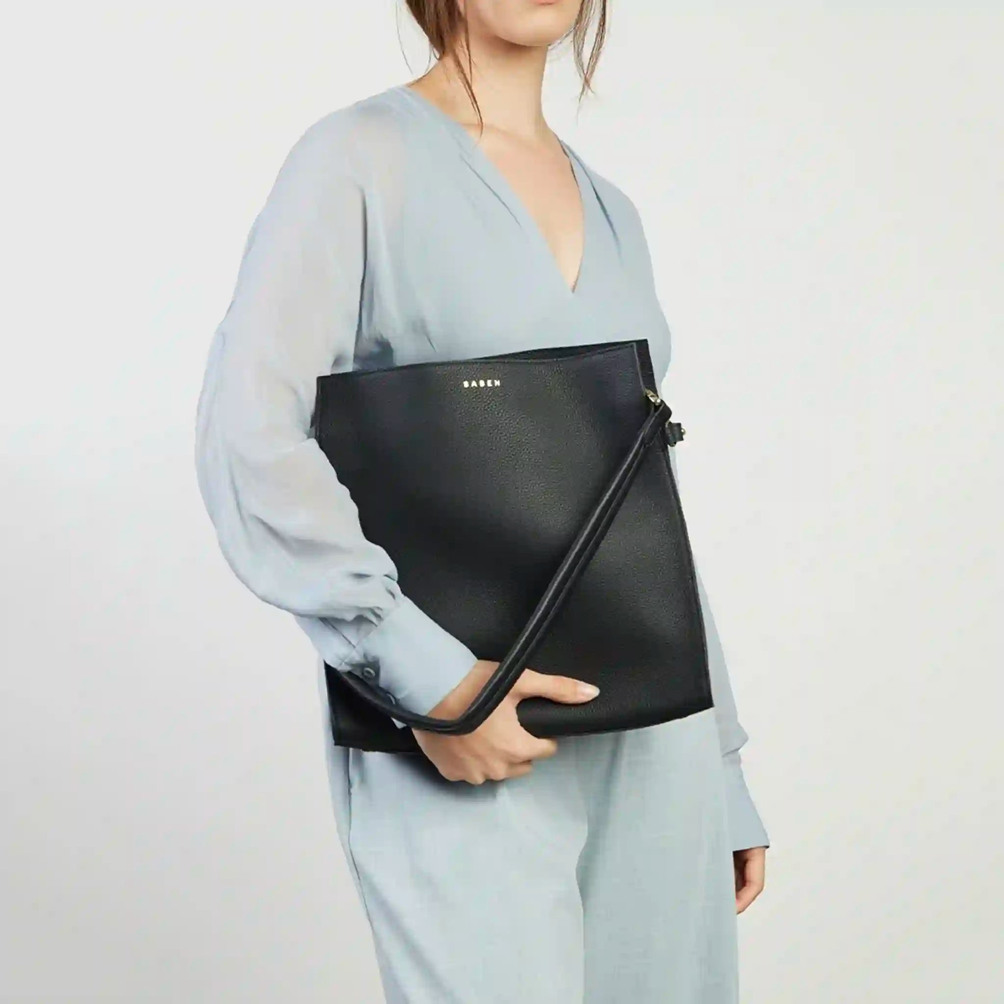 Person holding a black bag with a plain background