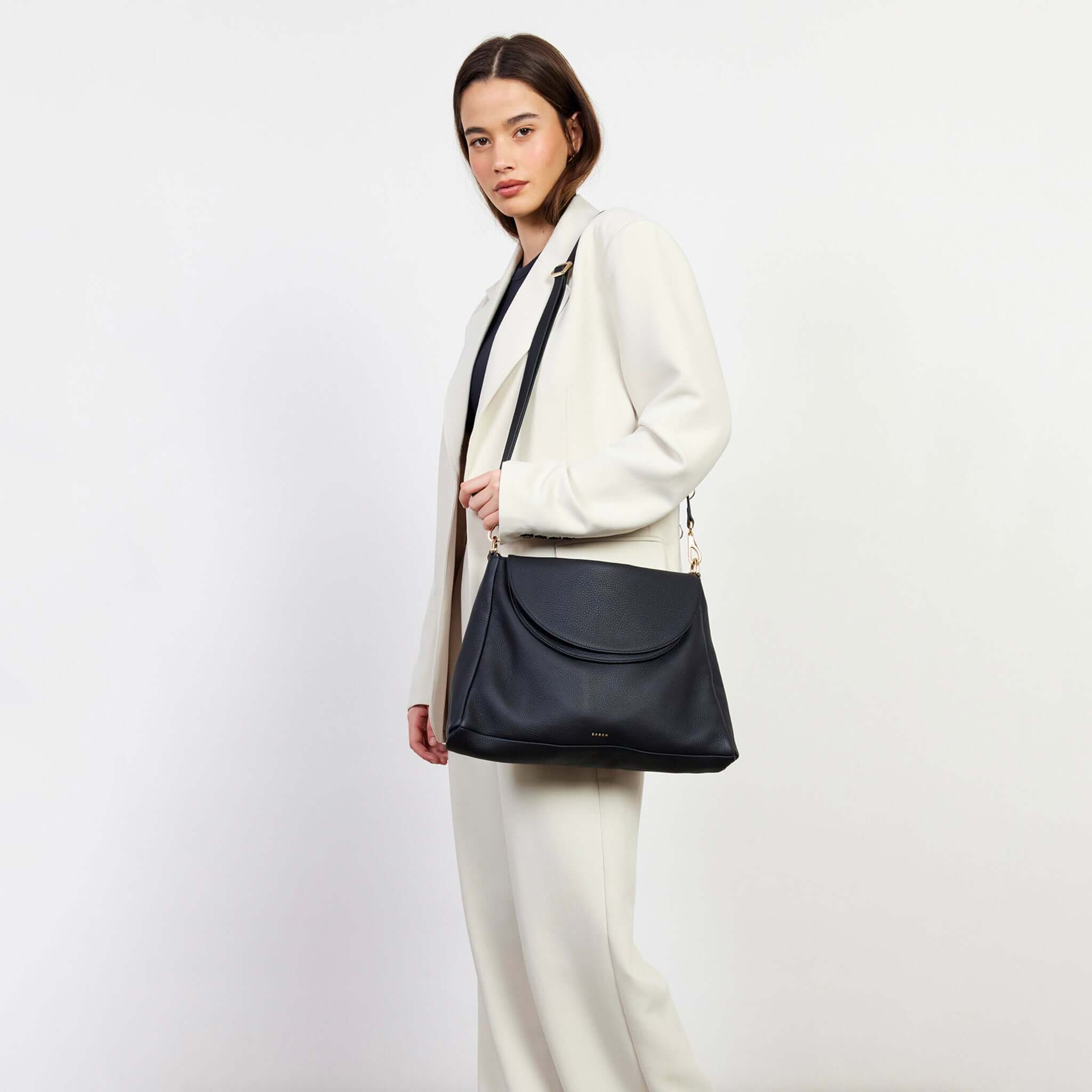 Alt Tag: Saben Becks Shoulder Bag - Black Luxe black leather shoulder bag with foldover panel, worn crossbody on model