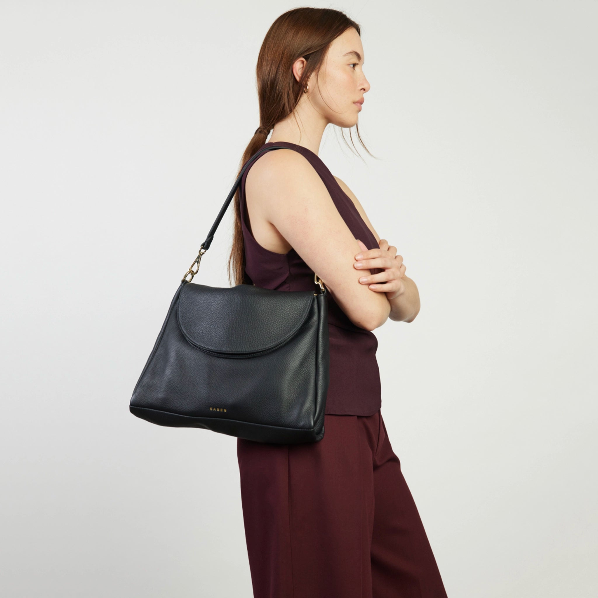 Woman carrying a black handbag on a plain background