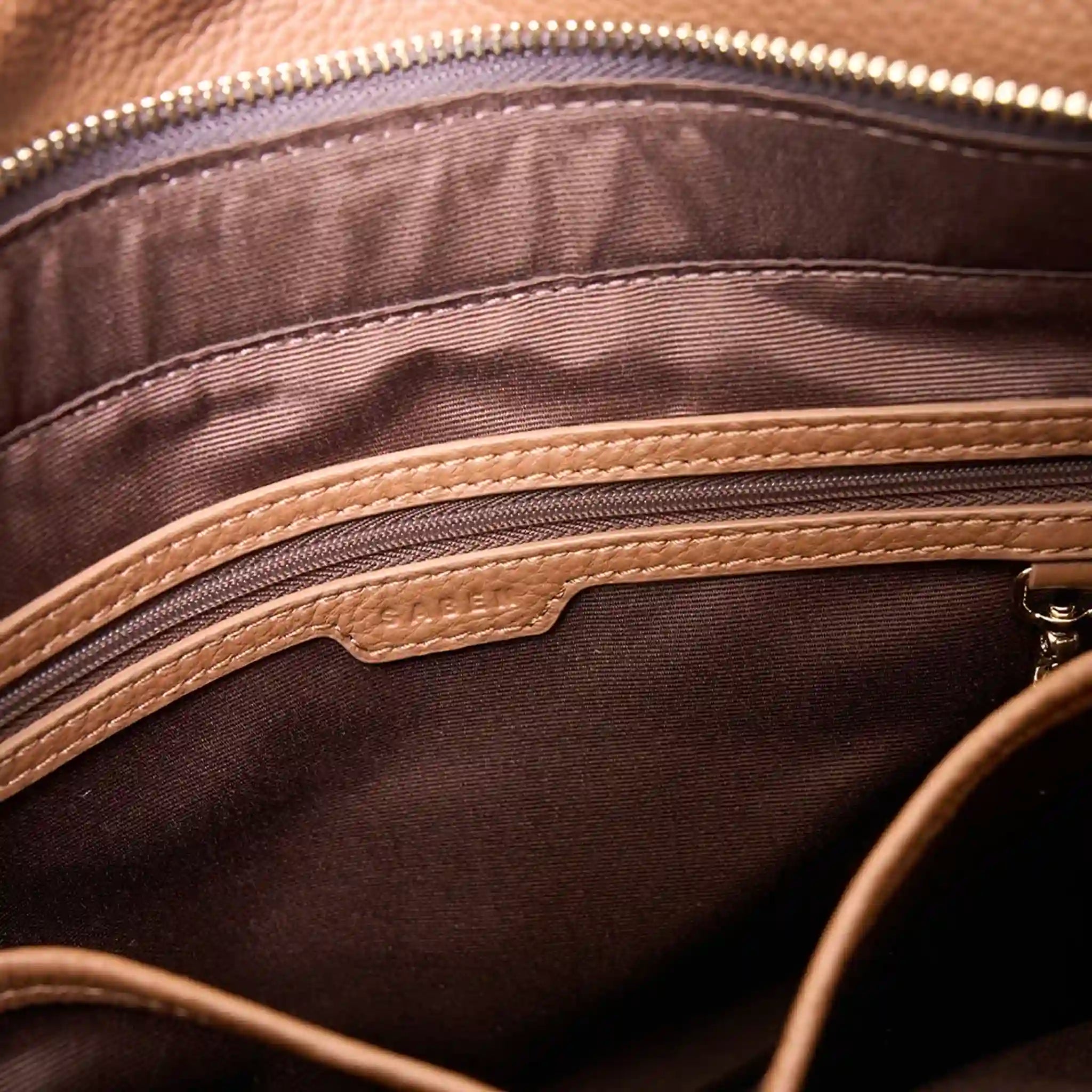 Close-up of a brown leather bag with a zipper