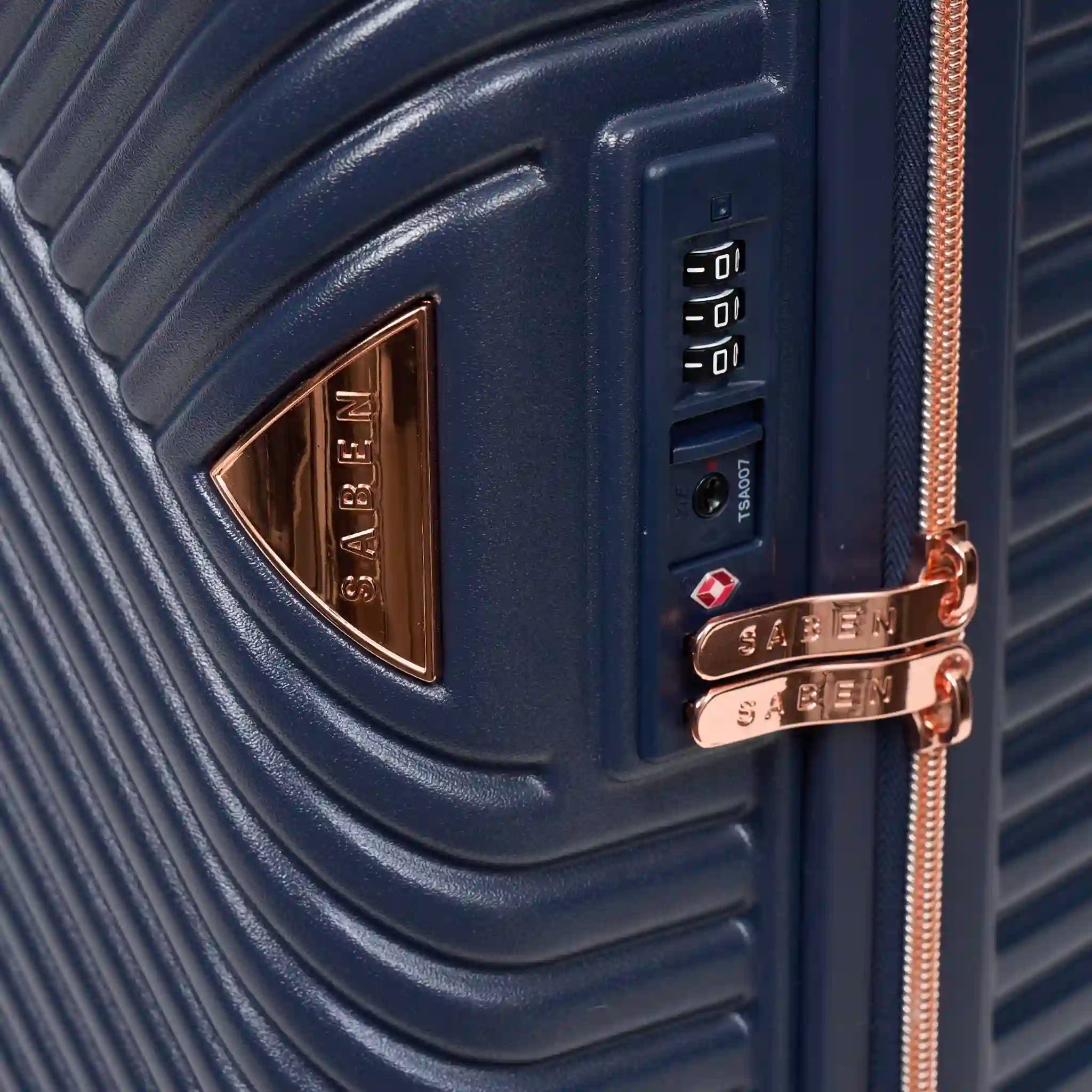 Close-up of a navy blue suitcase with rose gold accents and SABEN branding.