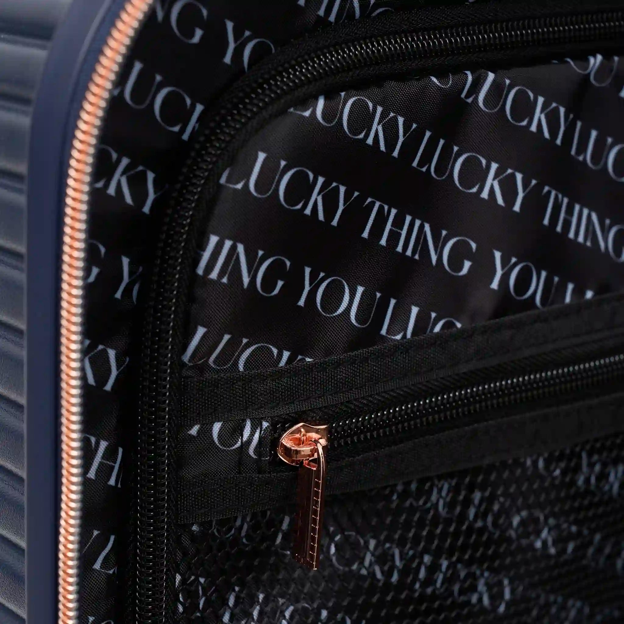 Close-up of a black bag with 'YOU LUCKY THING' text and gold zipper.