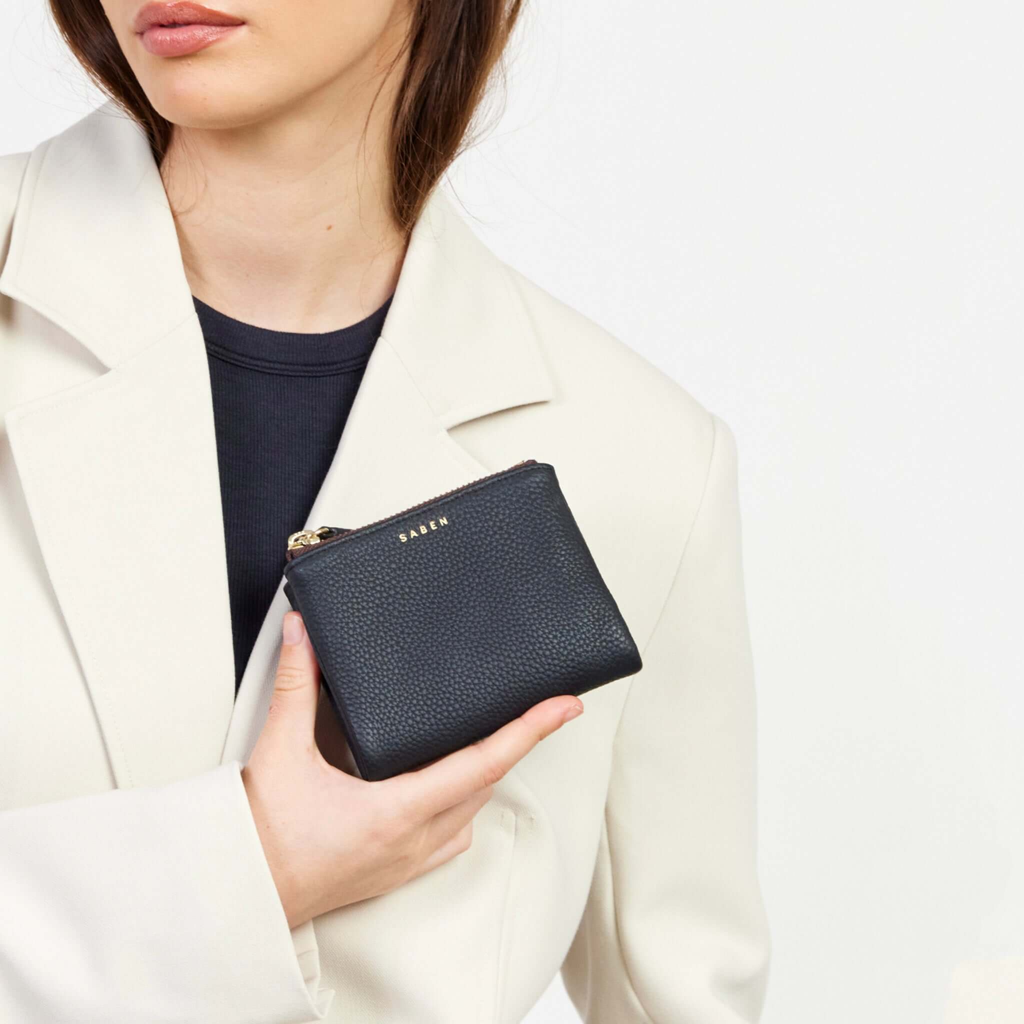 Saben Delilah Wallet - Black compact pebbled leather wallet with zip closure, held in hand