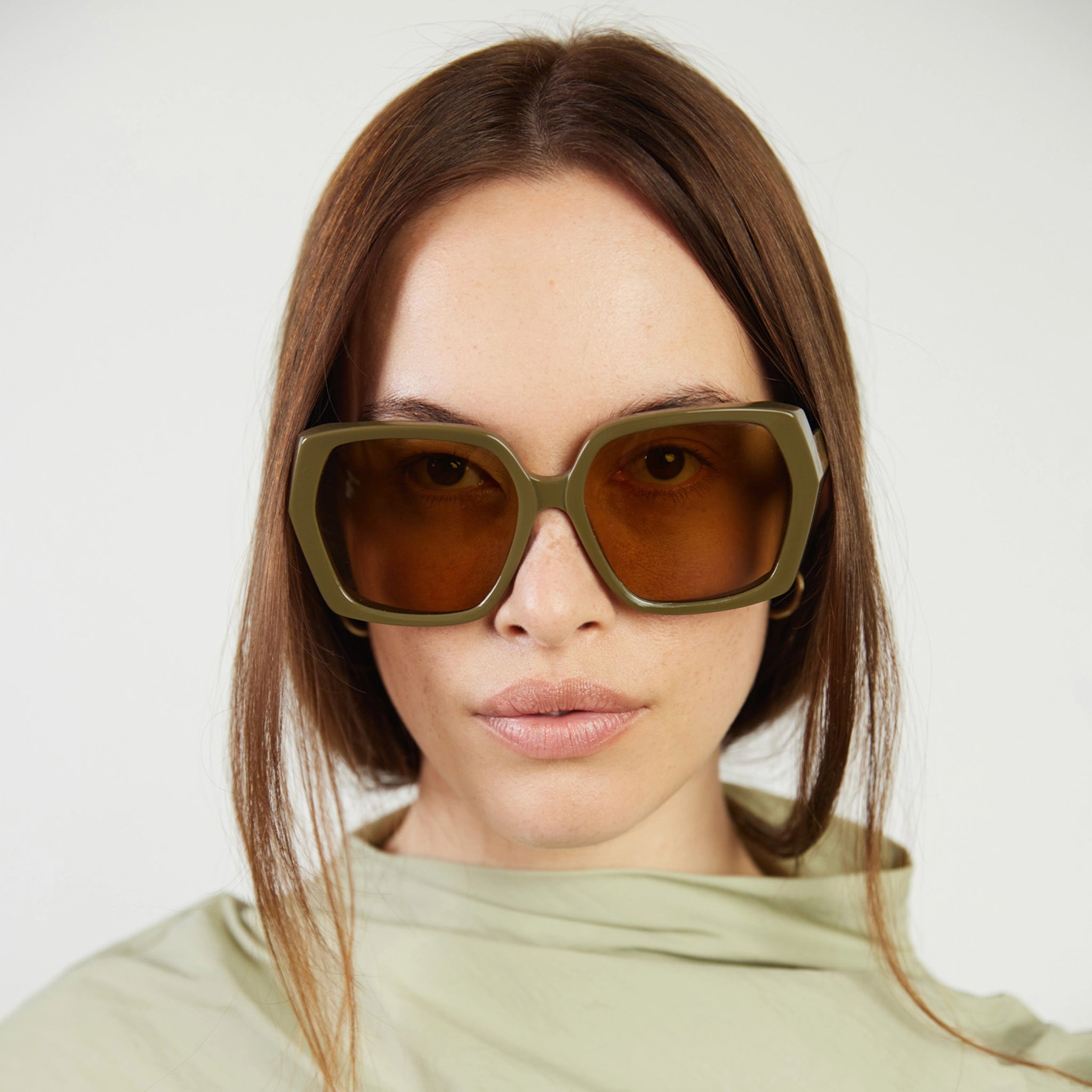 Woman wearing large sunglasses with a neutral background
