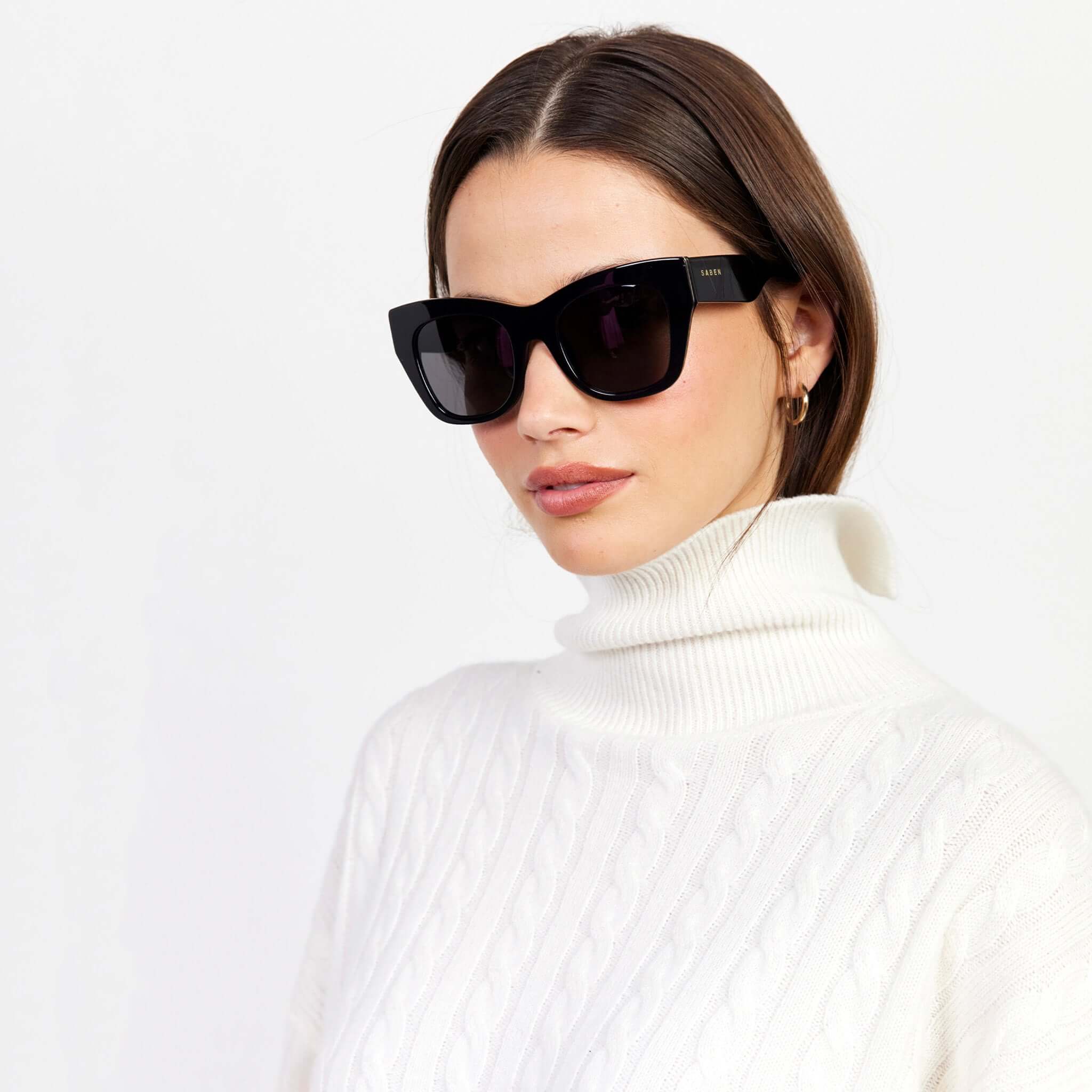 Alt Tag: Saben Eyewear Sloane Sunglasses - Black on model, elegant black cat-eye frame with pale gold hardware, natural acetate