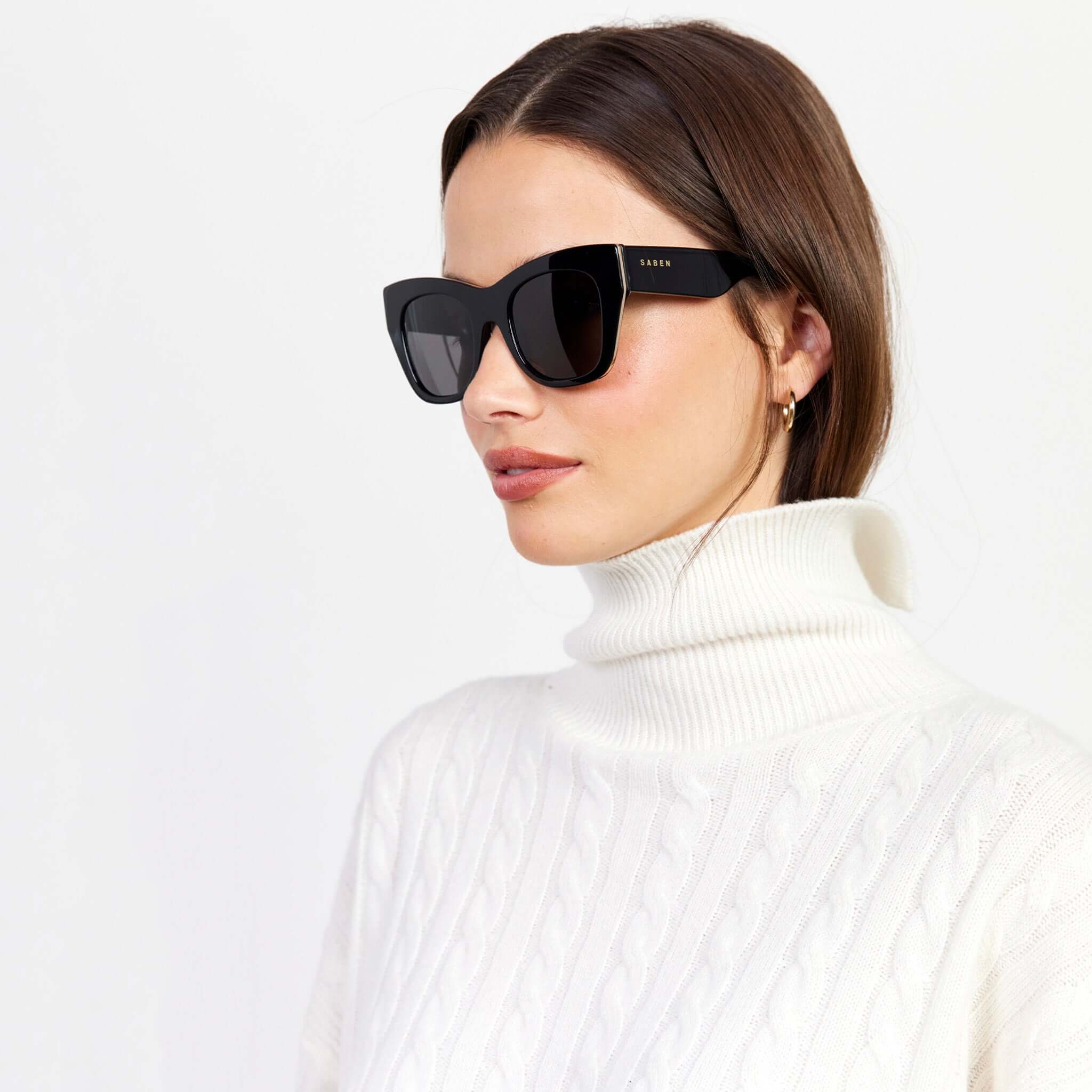 Saben Eyewear Sloane Sunglasses - Black on model, natural acetate frame with pale gold hardware, sculpting cat-eye lift
