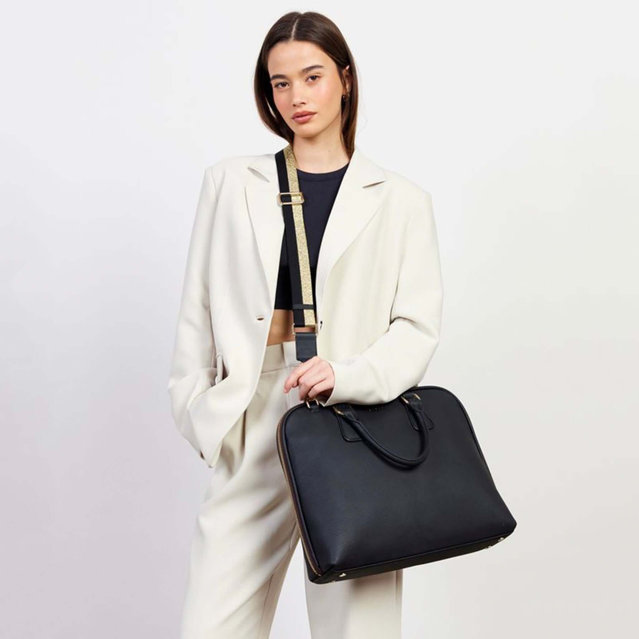Alt Tag: Model wearing Saben Feature Webbing Strap - Gold & Black Stripe with black Saben bag, cotton webbing, leather trim, gold hardware