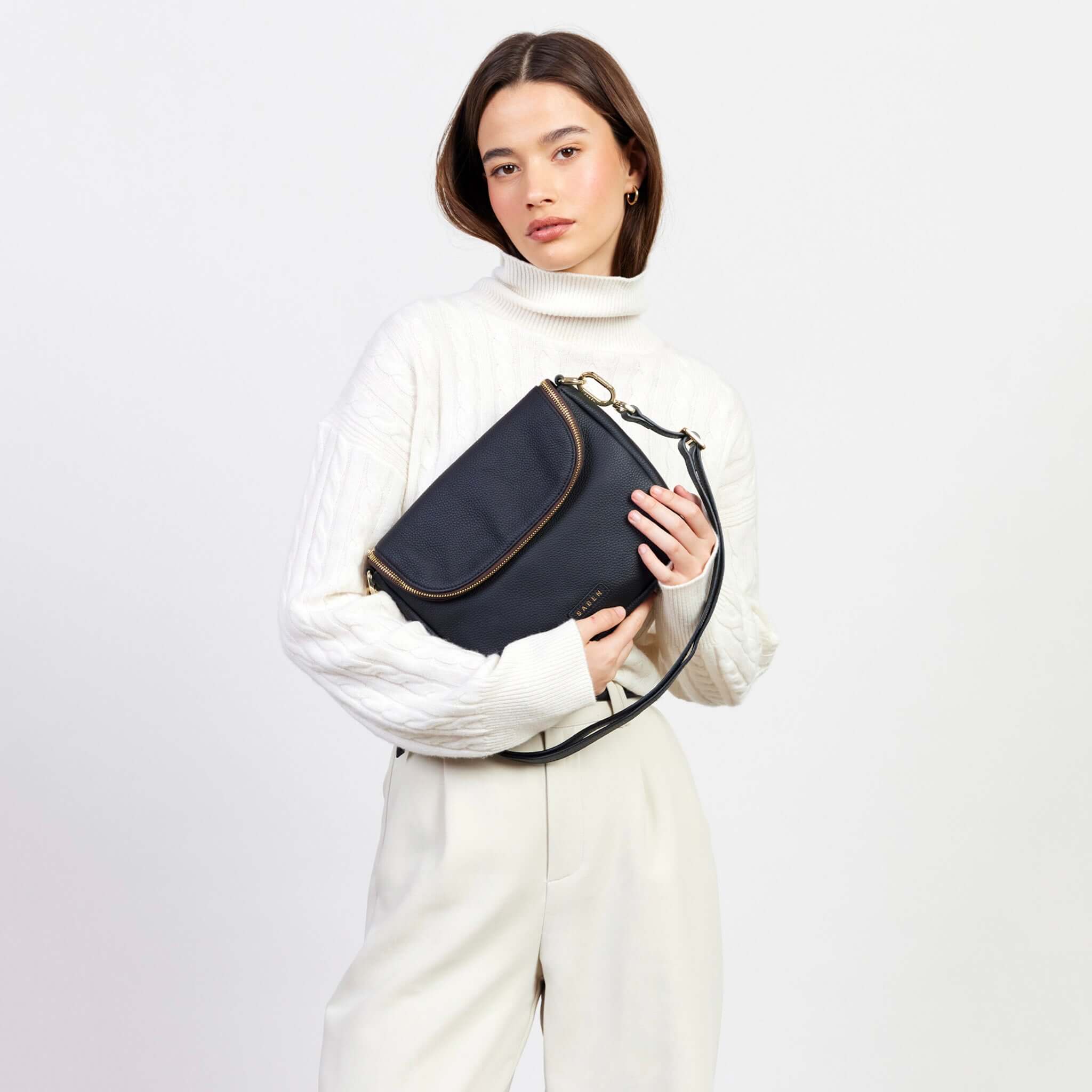 Alt Tag: Model holding Saben Fifi Crossbody Bag - Black with draped pocket detail and pebbled leather, chic compact crossbody