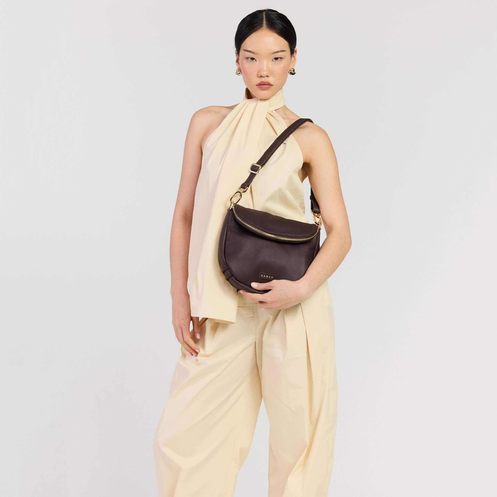 Saben Fifi Crossbody Bag - Cacao showcased on model wearing light outfit, highlighting its chic design and color.