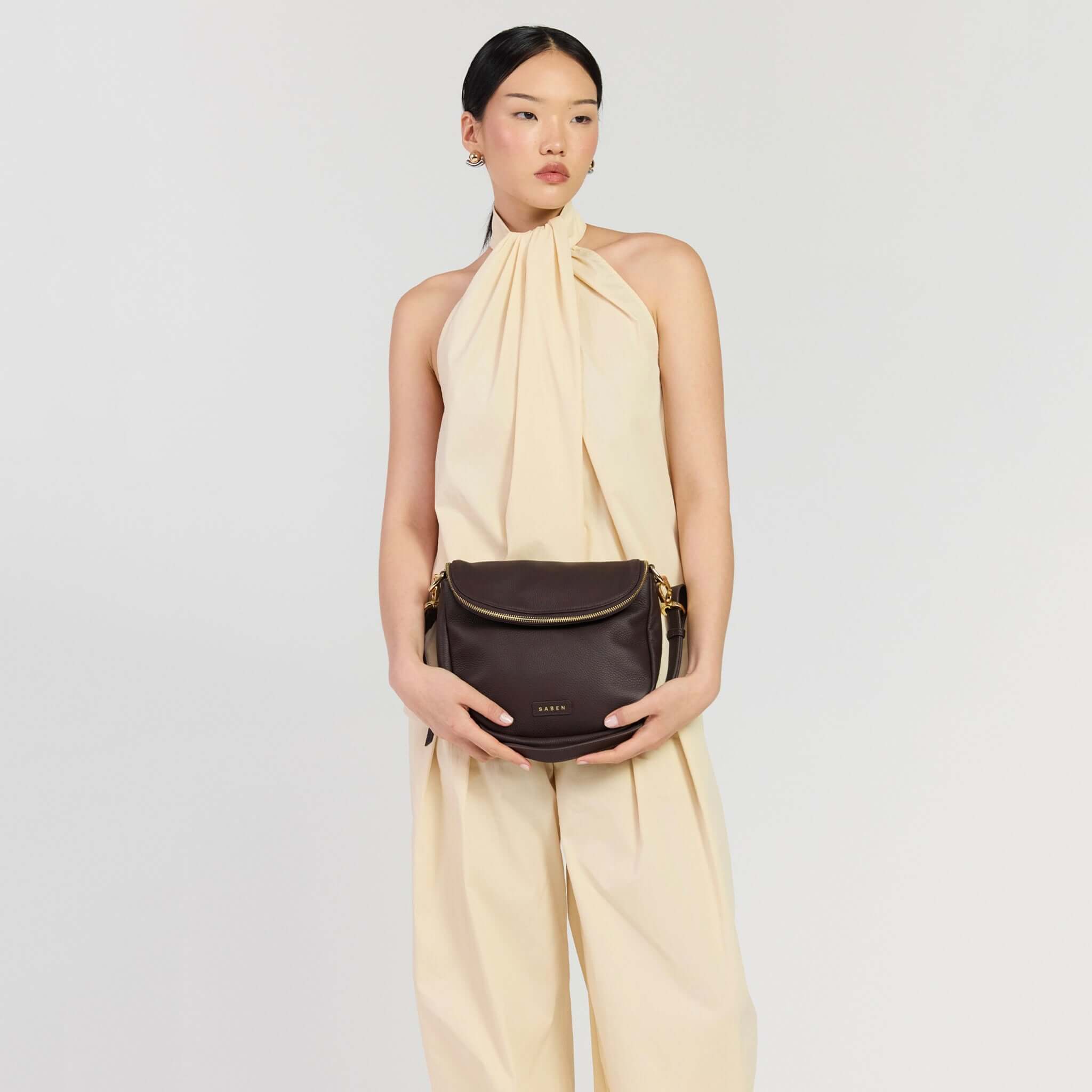 A model showcasing the Saben Fifi Crossbody Bag - Cacao, wearing a fashionable outfit.