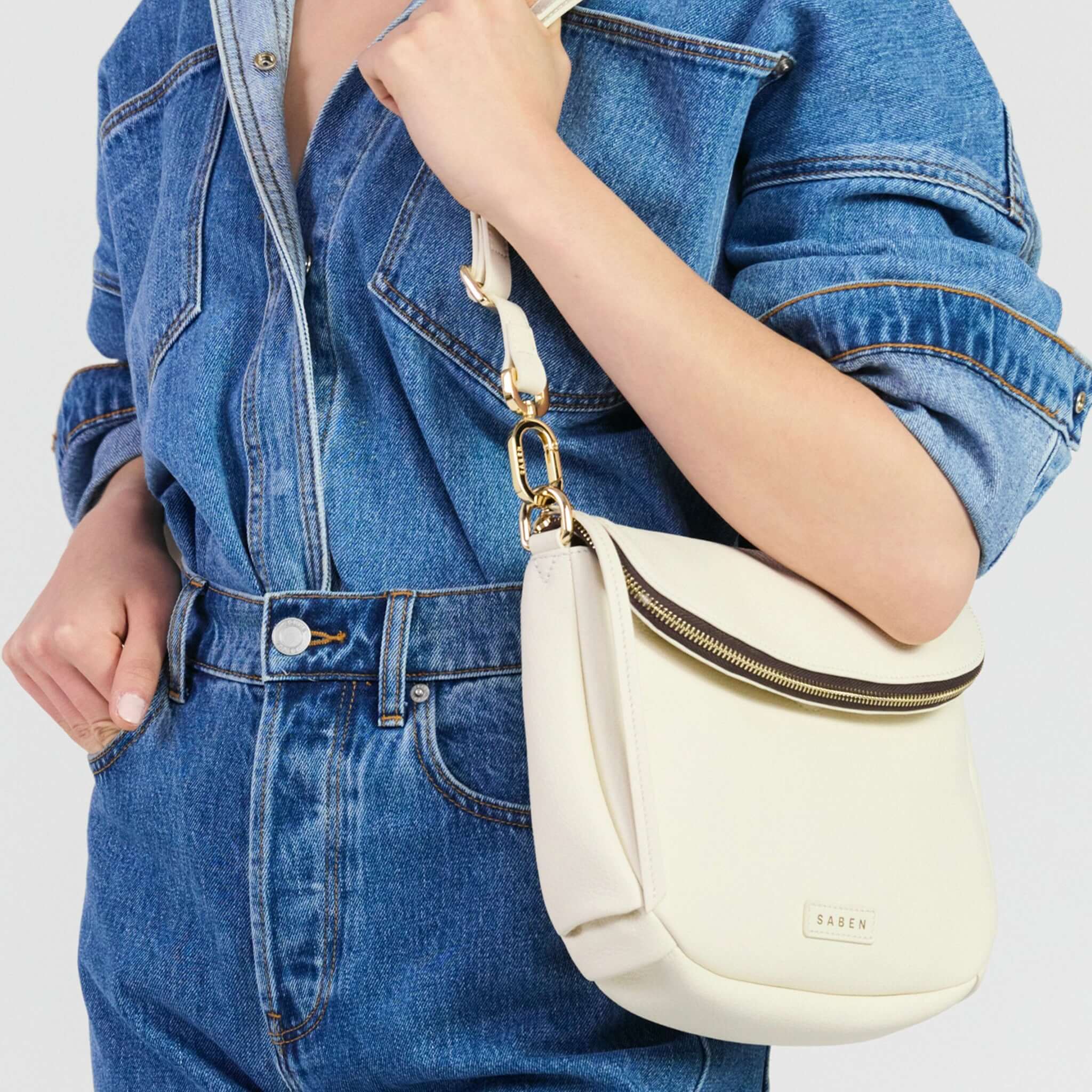 Saben Fifi Crossbody Bag - Quartz held by a person wearing a denim outfit, showcasing its stylish design and compact size.