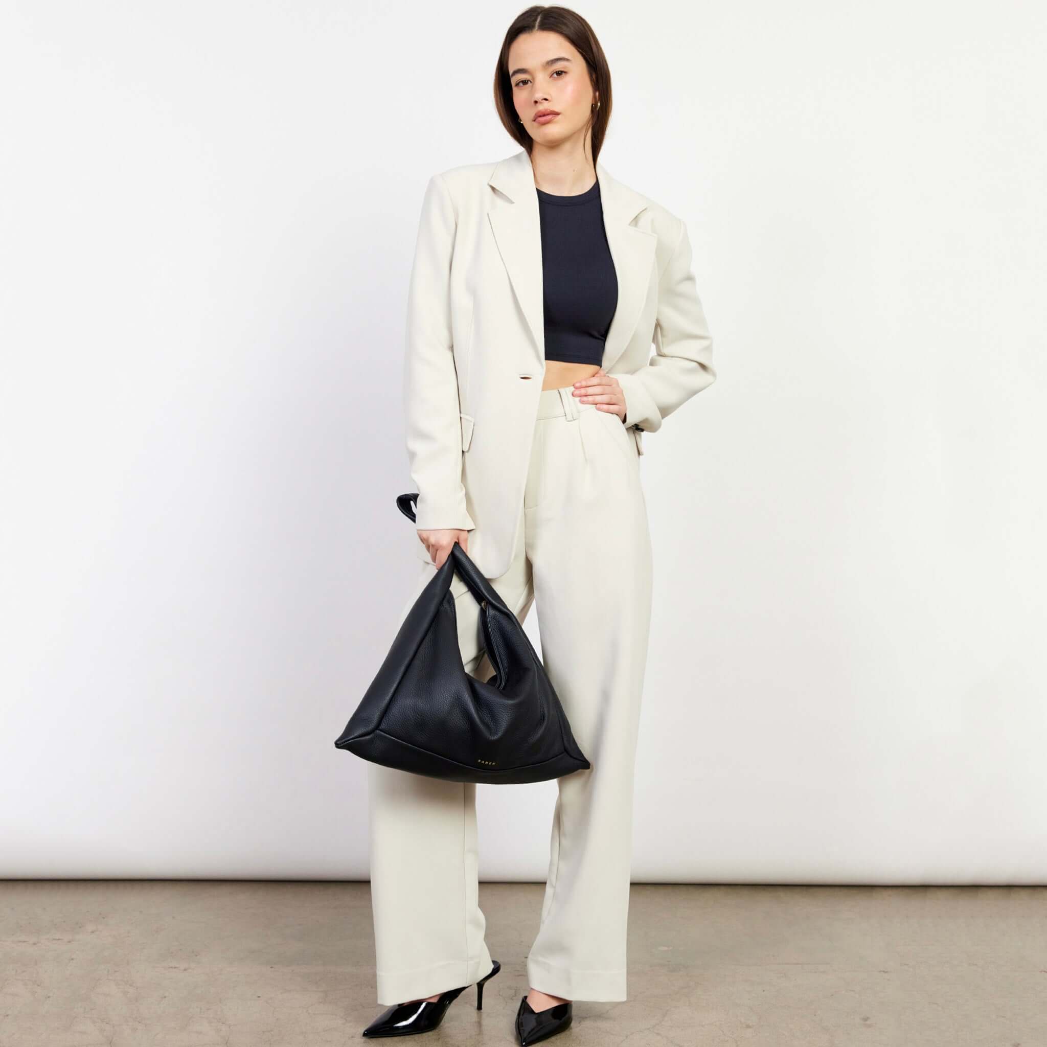 Alt Tag: Saben Haze Shoulder Bag - Black Luxe black cowhide slouch shoulder bag carried by model in cream suit