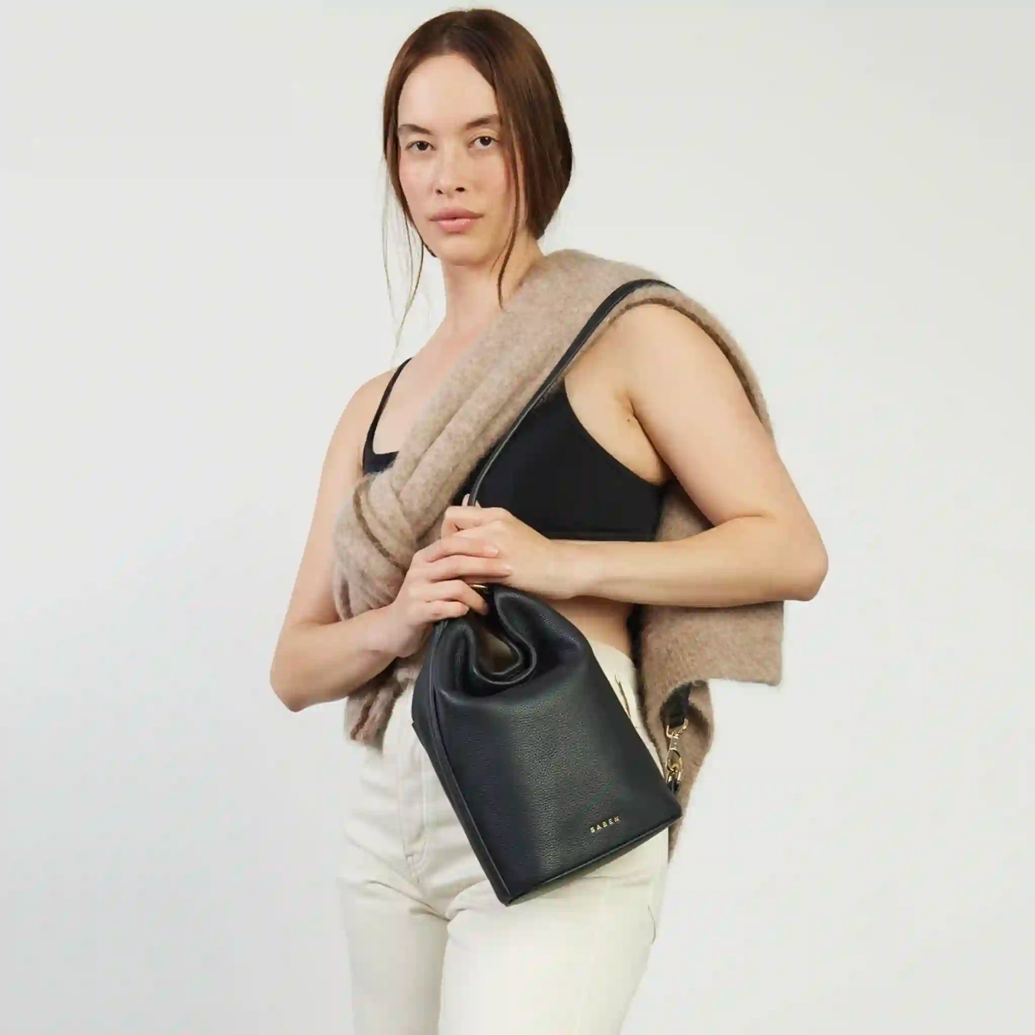 Woman holding a black handbag against a white background