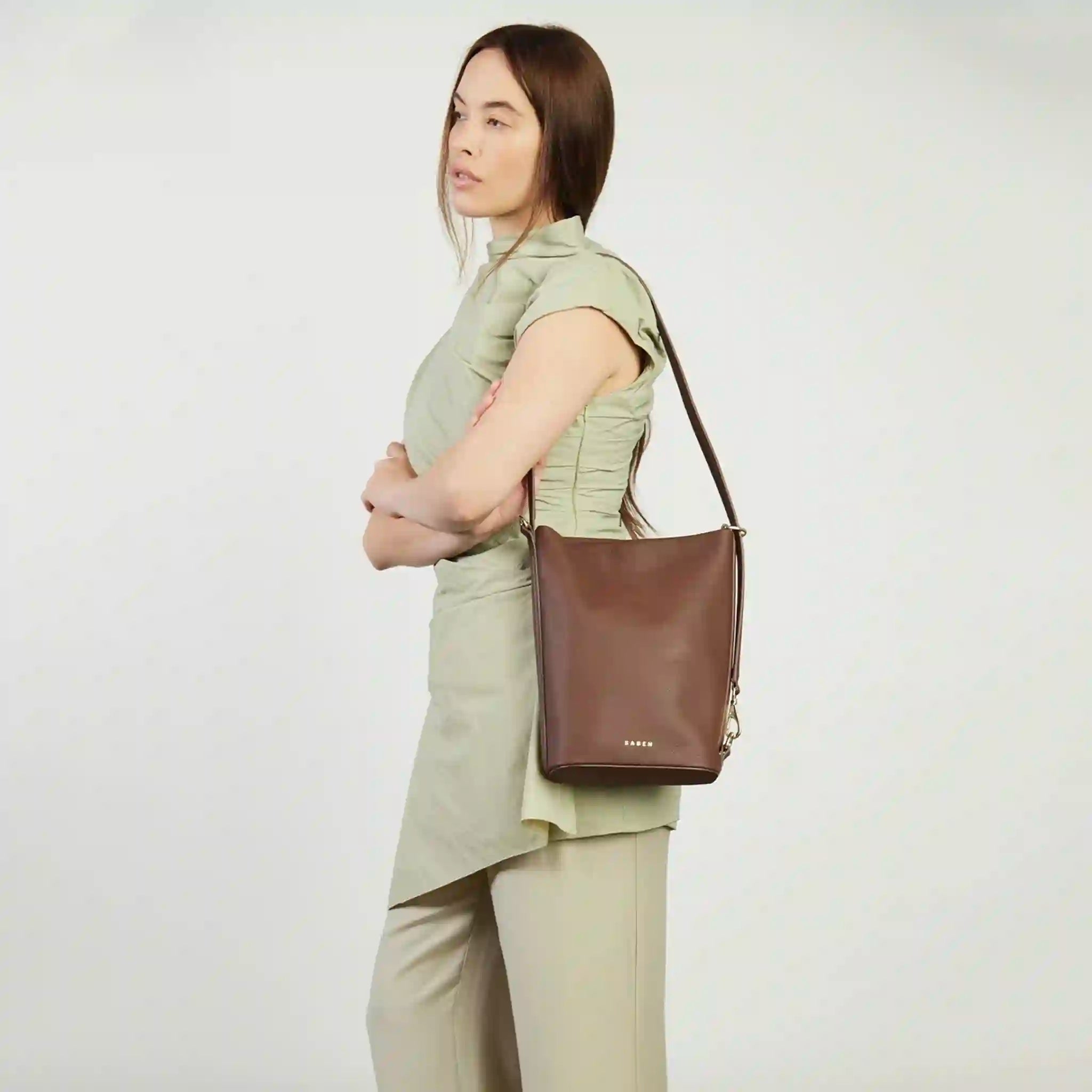 Woman holding a brown leather bag against a plain background
