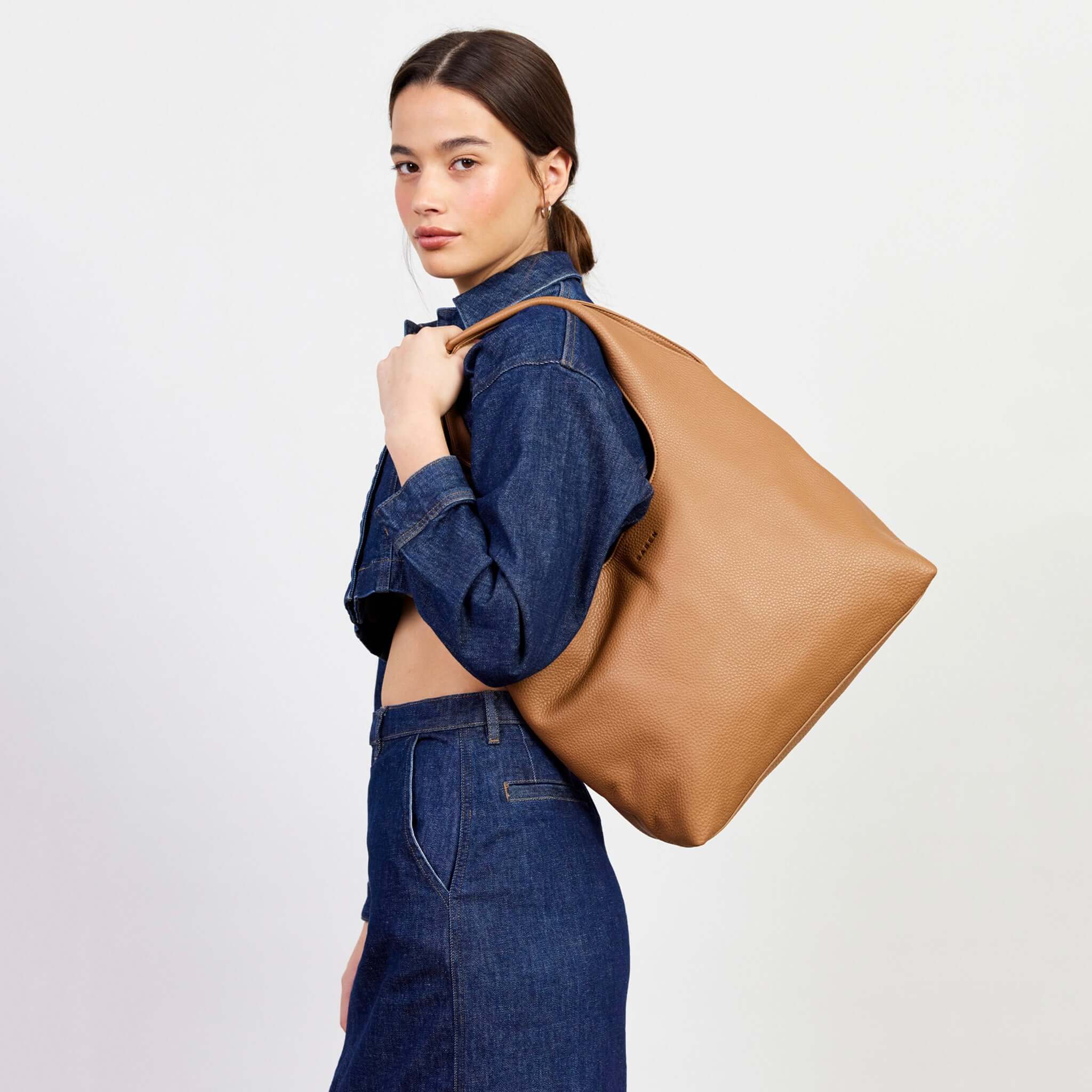 Alt Tag: Saben Kip Shoulder Bag - Lightly Milled Toffee slouchy toffee leather shoulder tote on model, roomy everyday essentials bag