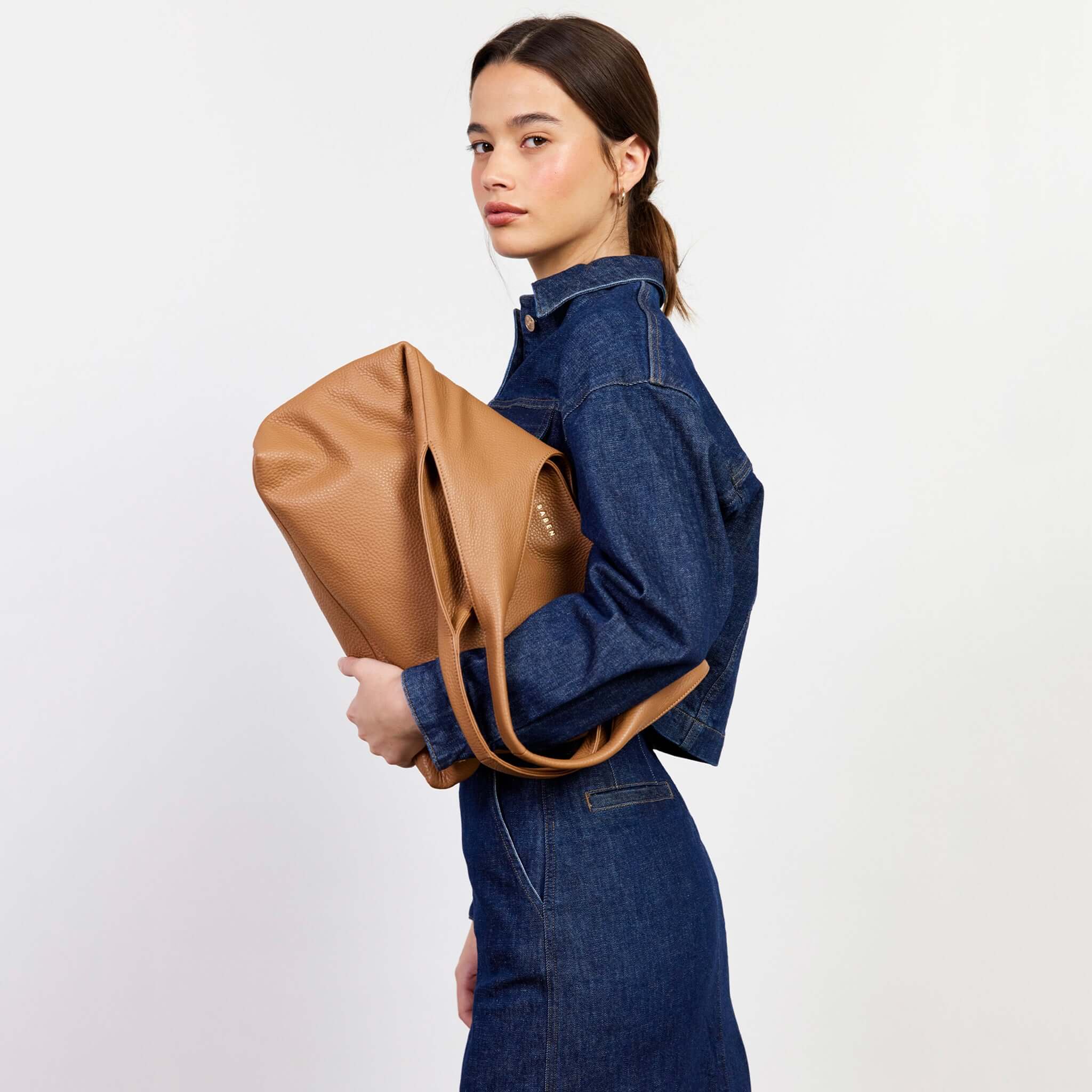 Alt Tag: Saben Kip Shoulder Bag - Lightly Milled Toffee worn on shoulder by model, slouchy toffee leather carryall with relaxed drape