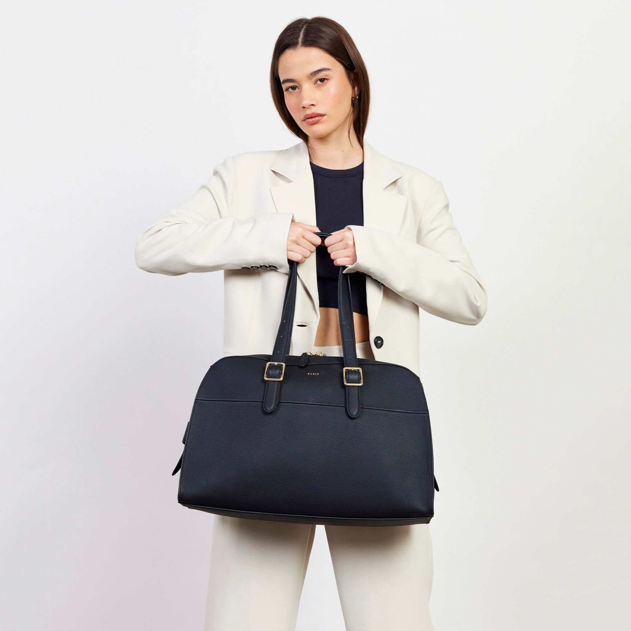 Alt Tag: Saben Marti Shoulder Bag - Black structured bowler bag with buckle shoulder straps and zip closure, carried by model