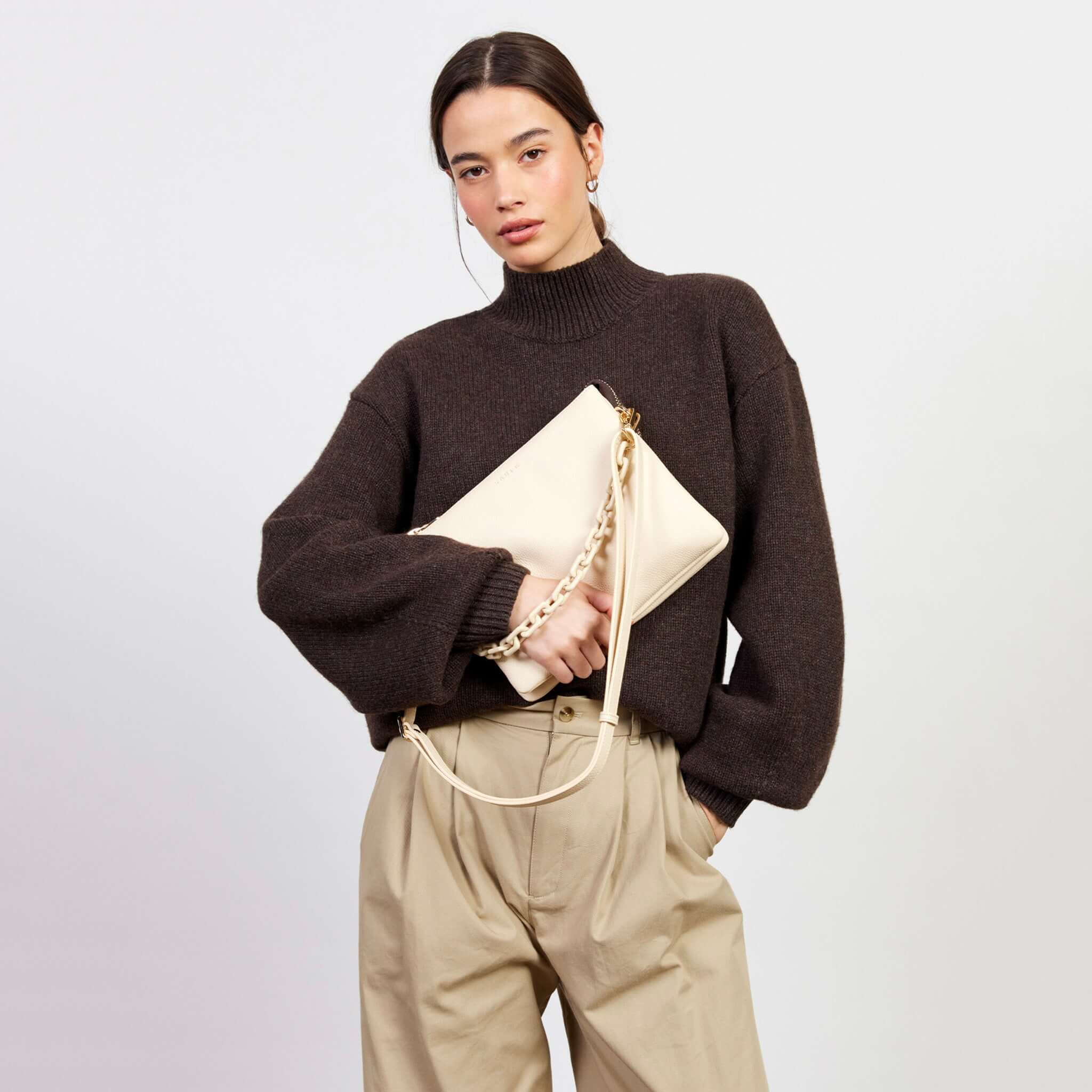 Alt Tag: Model holding Saben Matilda Crossbody Bag - Vanilla with Tonal Chain, luxe vanilla leather crossbody with tonal chain strap