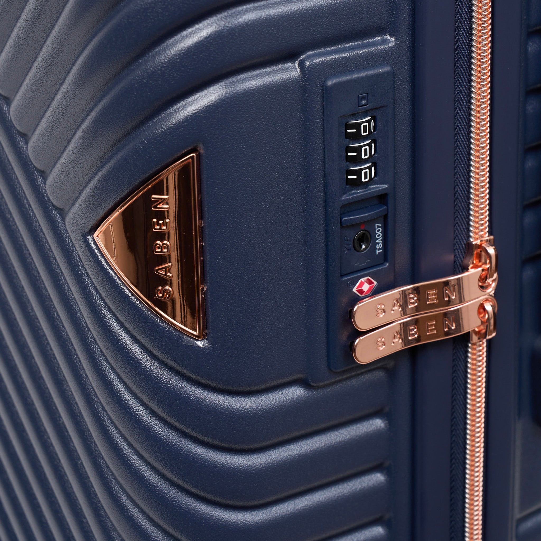 Close-up of a navy blue suitcase with a gold Saben logo and combination lock.