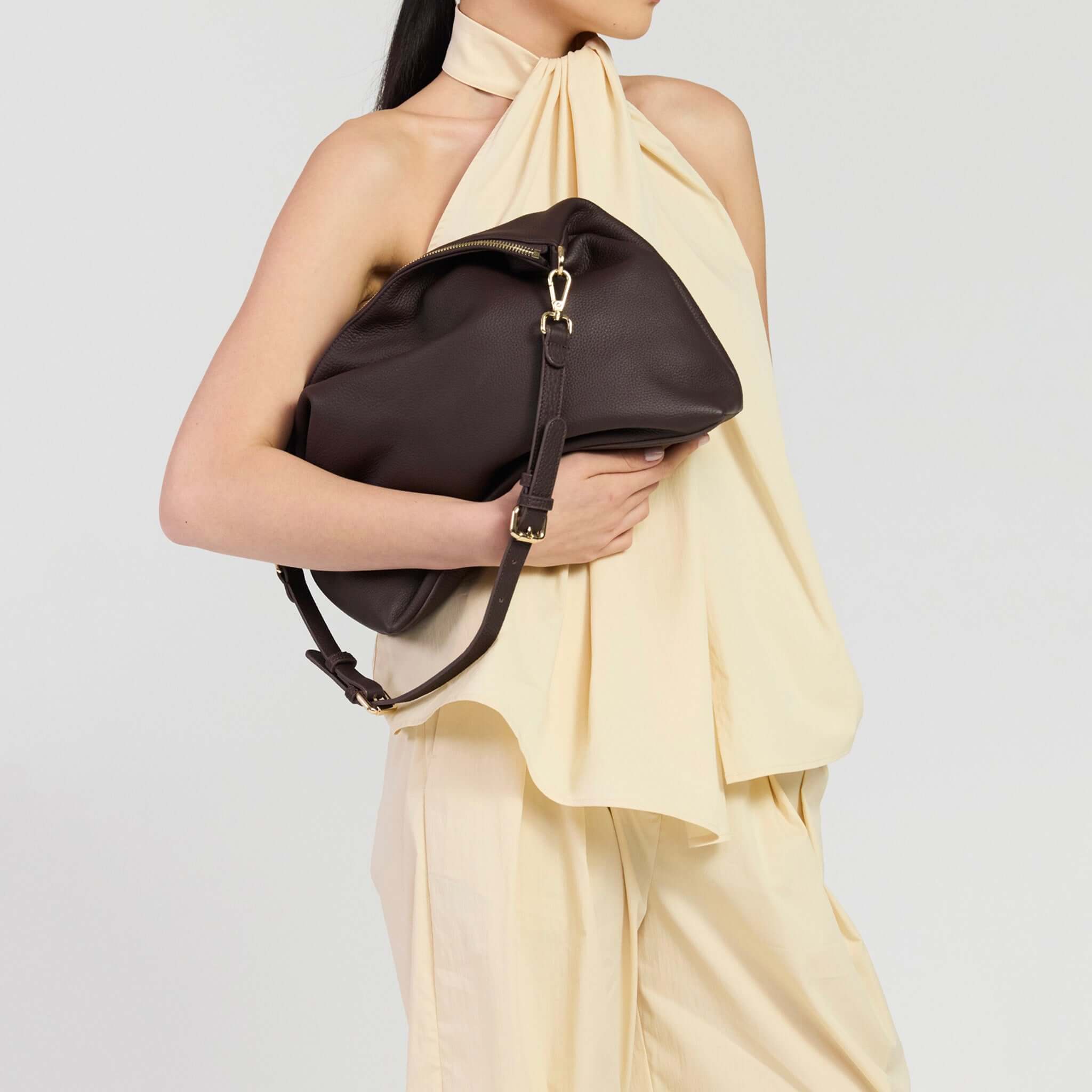 Woman holding Saben Miki Shoulder Bag - Cacao Luxe in soft leather, styled with a beige top.
