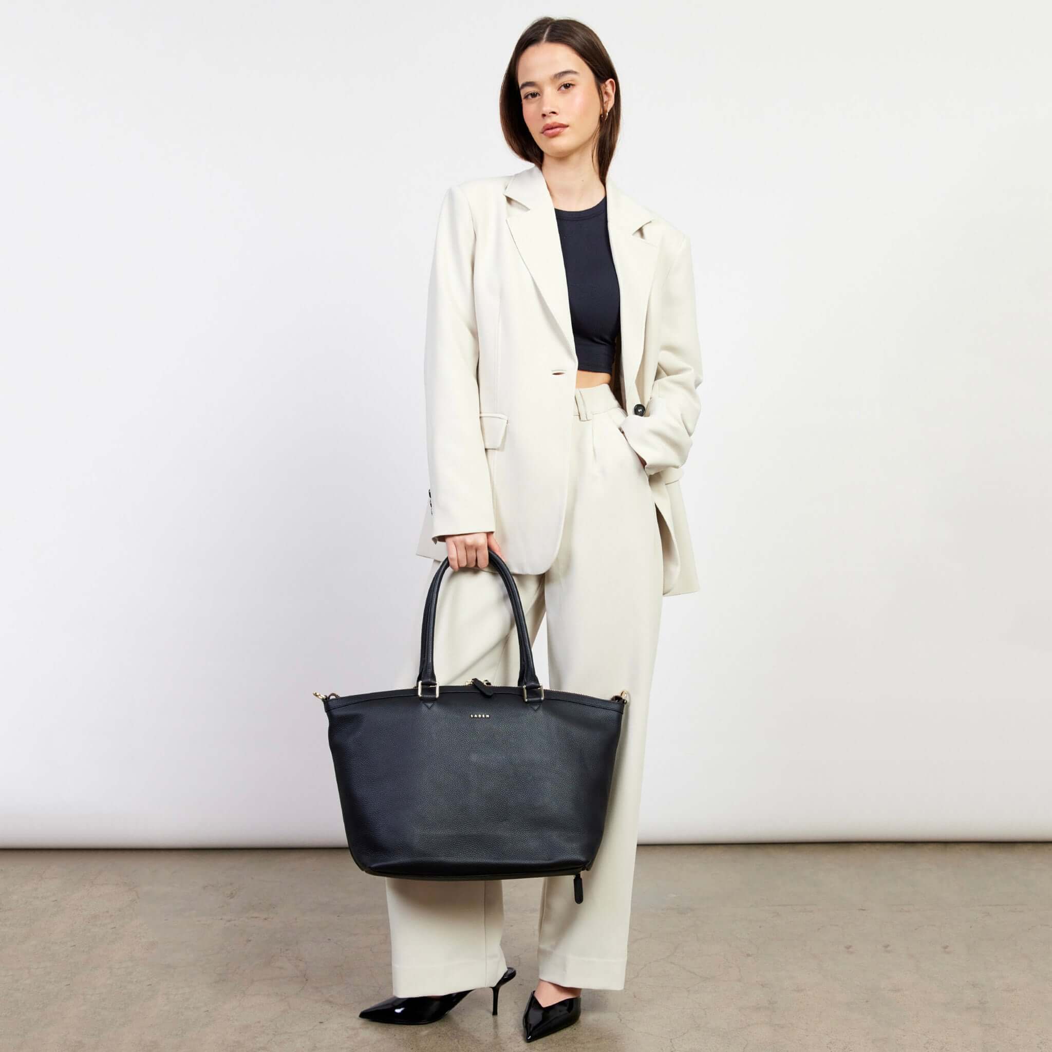 Saben Milan Carry-All Bag - Black tote held by model, spacious everyday carry-all with long handles and sleek black finish