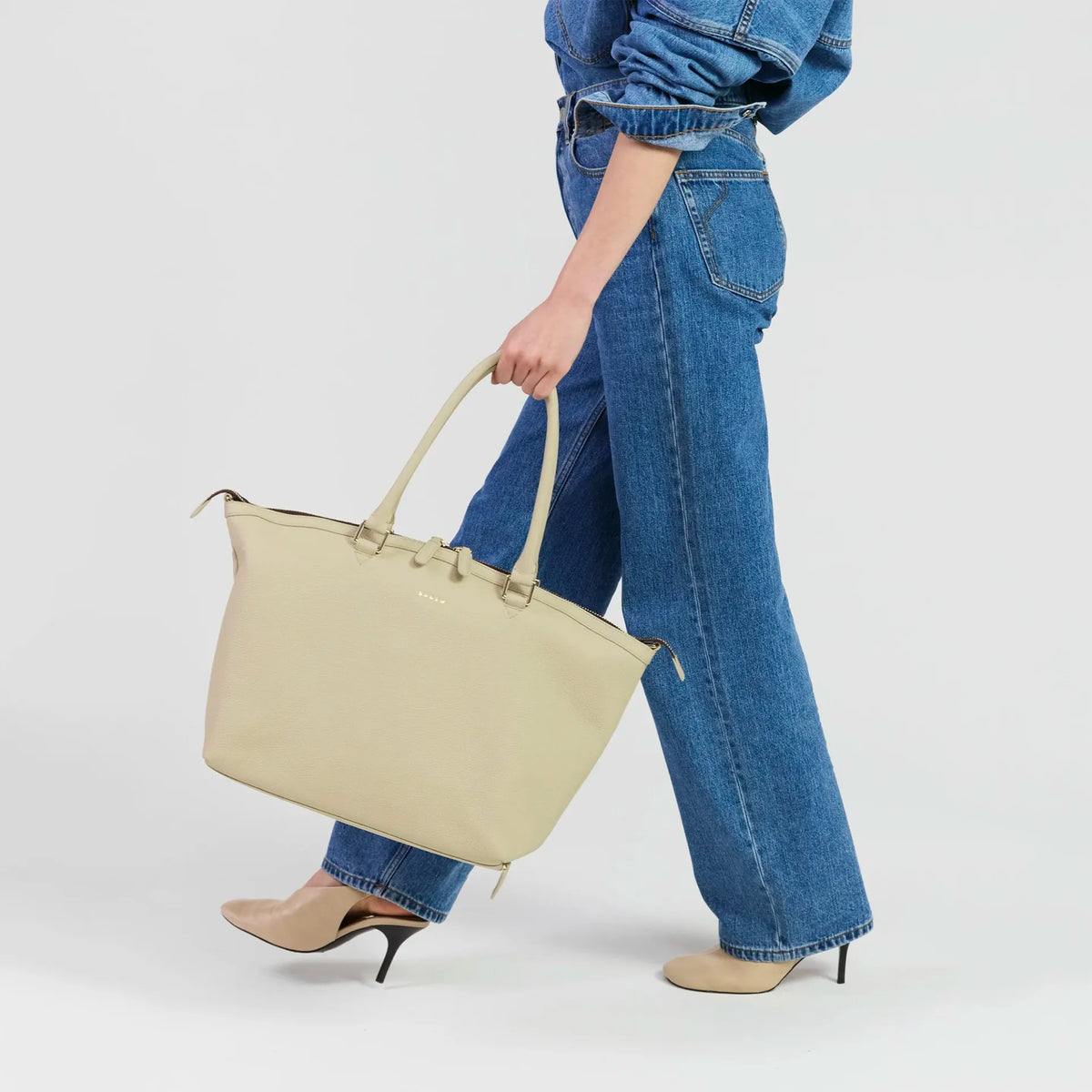 Saben Milan Carry-All Bag - Oyster carried at the side by a model in wide-leg denim