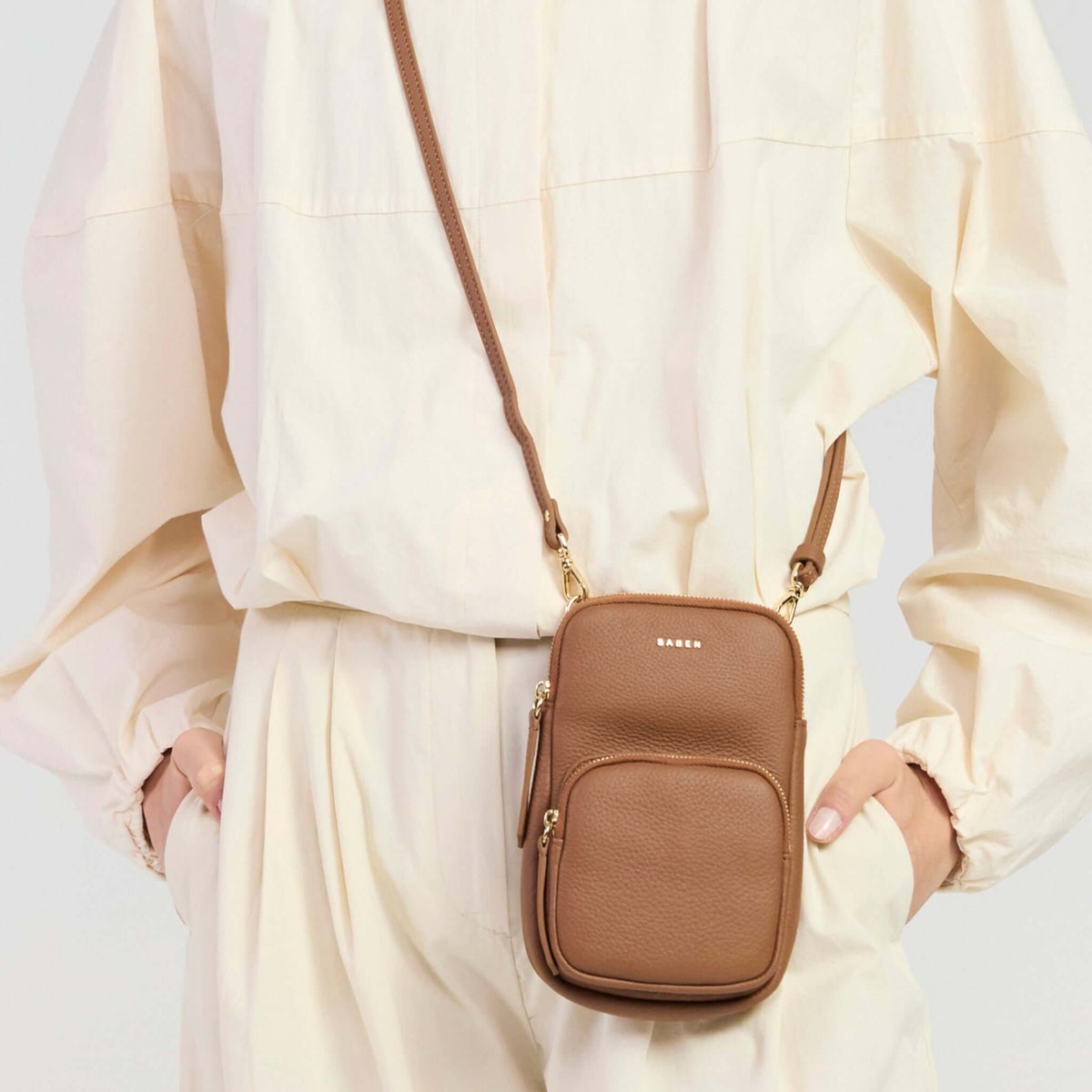 Saben Nikko Pocket Phone Sling - Tan Luxe worn as a crossbody bag by a model in neutral outfit.