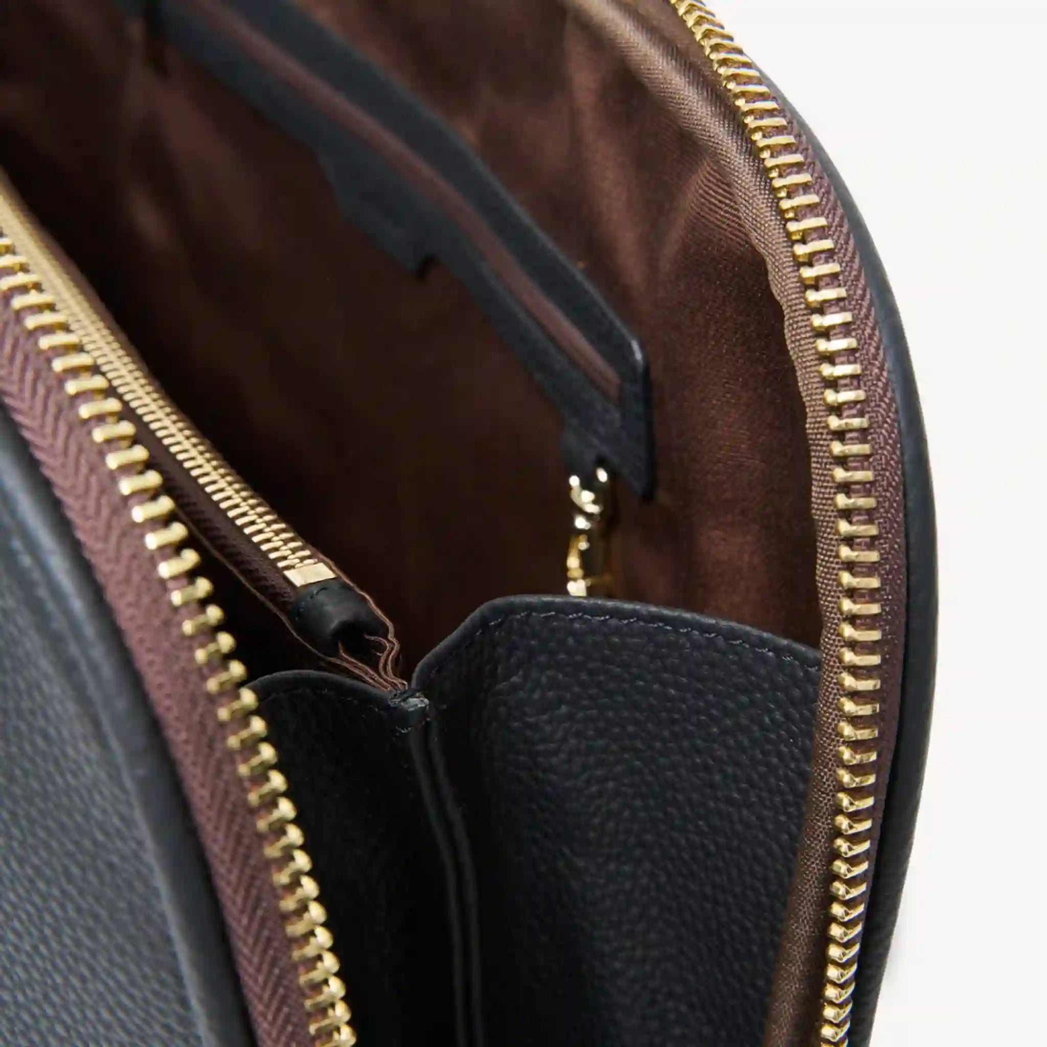 Close-up of a leather bag with gold zipper and brown interior.