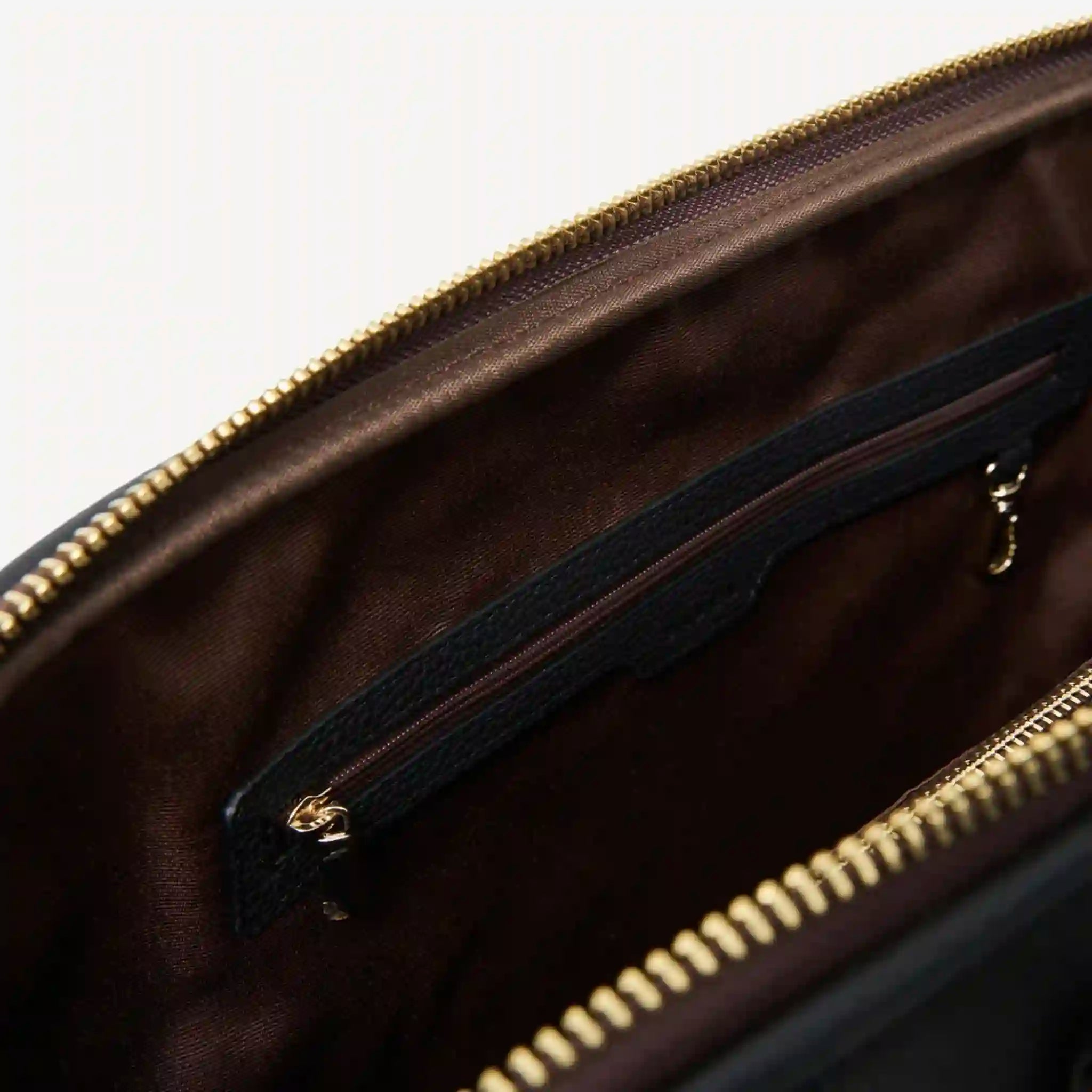 Brown leather bag with gold zipper on a white background