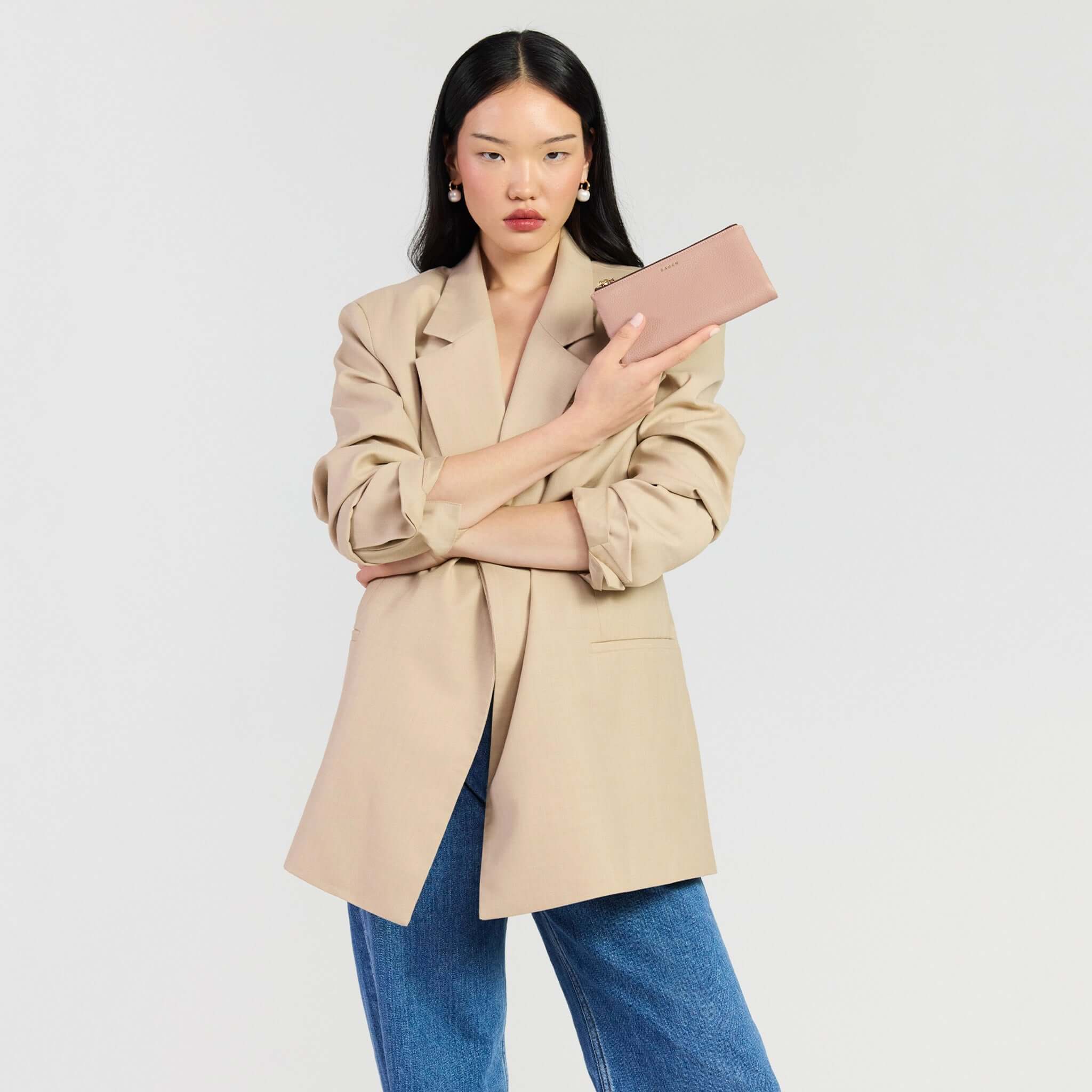 Saben Sam Wallet - Rosewater held by model in a stylish beige blazer and jeans.