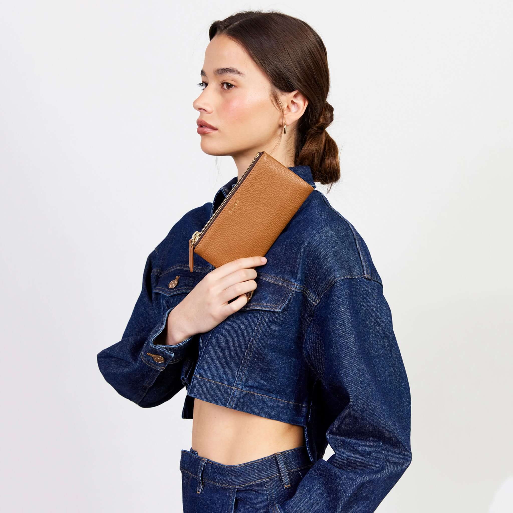 Alt Tag: Saben Sam Wallet - Toffee soft leather zip wallet with gold hardware, held by model