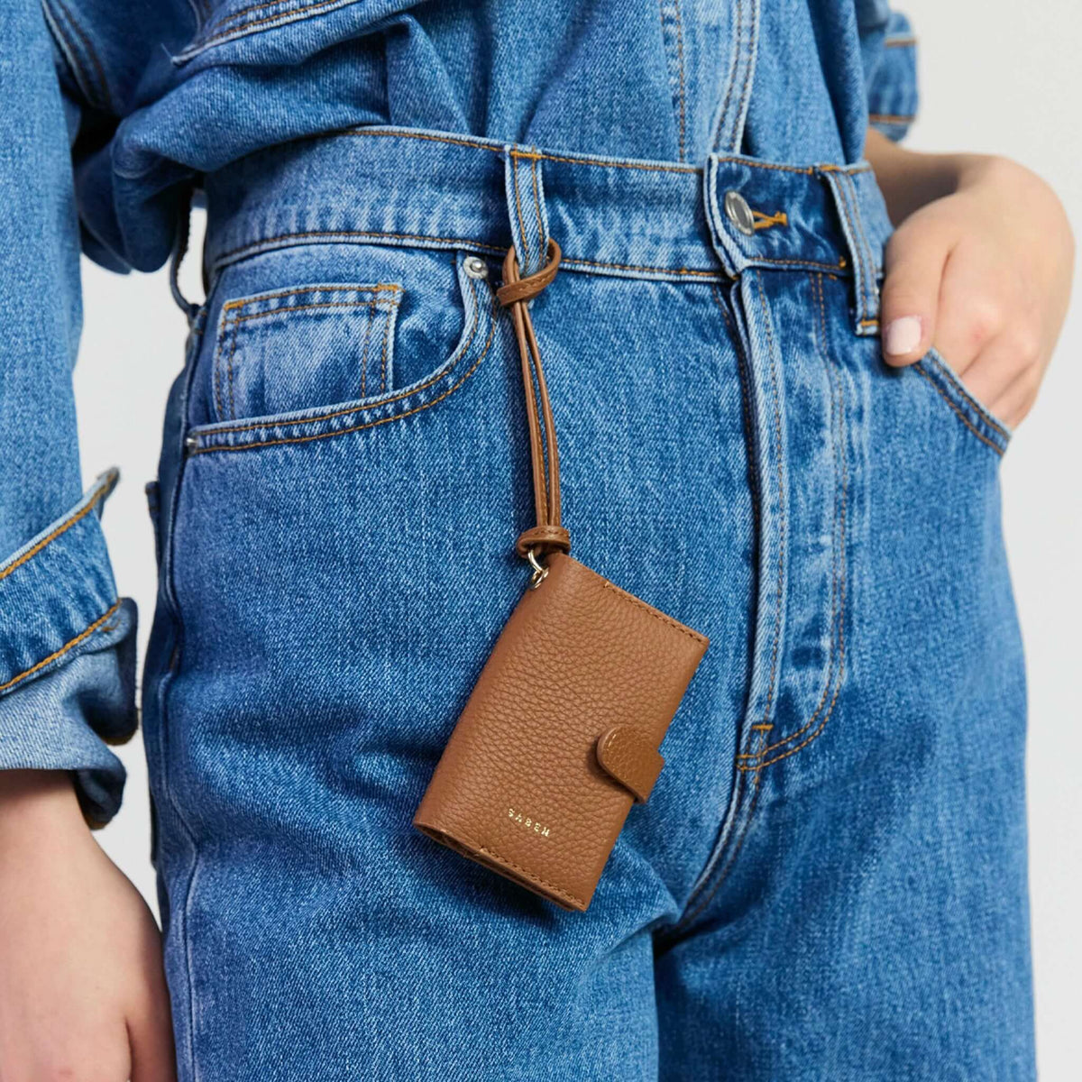 Saben Sid Card Holder - Tan attached to a stylish denim outfit, showcasing its compact design and functionality.