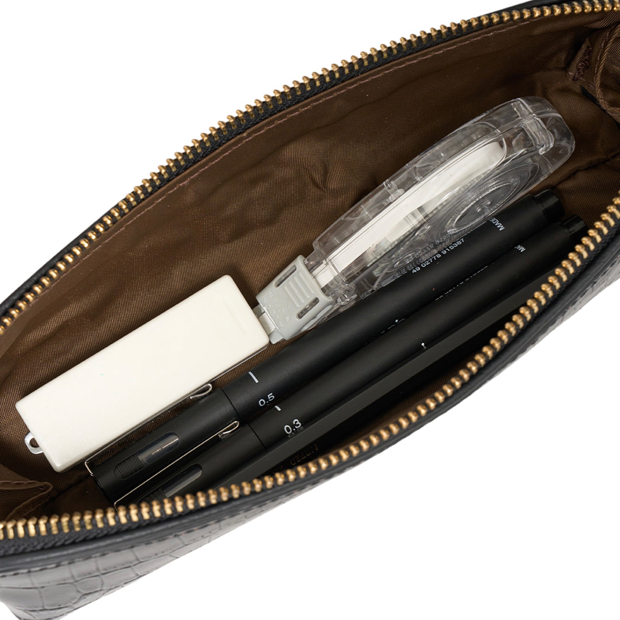 Open leather pouch with stationery items including pens and a ruler.
