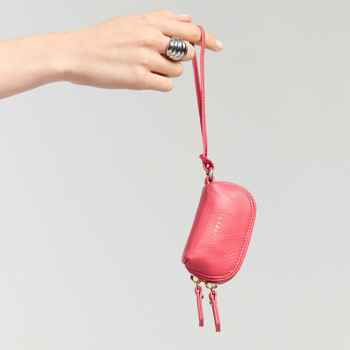 Saben Tarin Small Wristlet Pouch - Azalea being held with a stylish ring, showcasing its practical design and vibrant color.