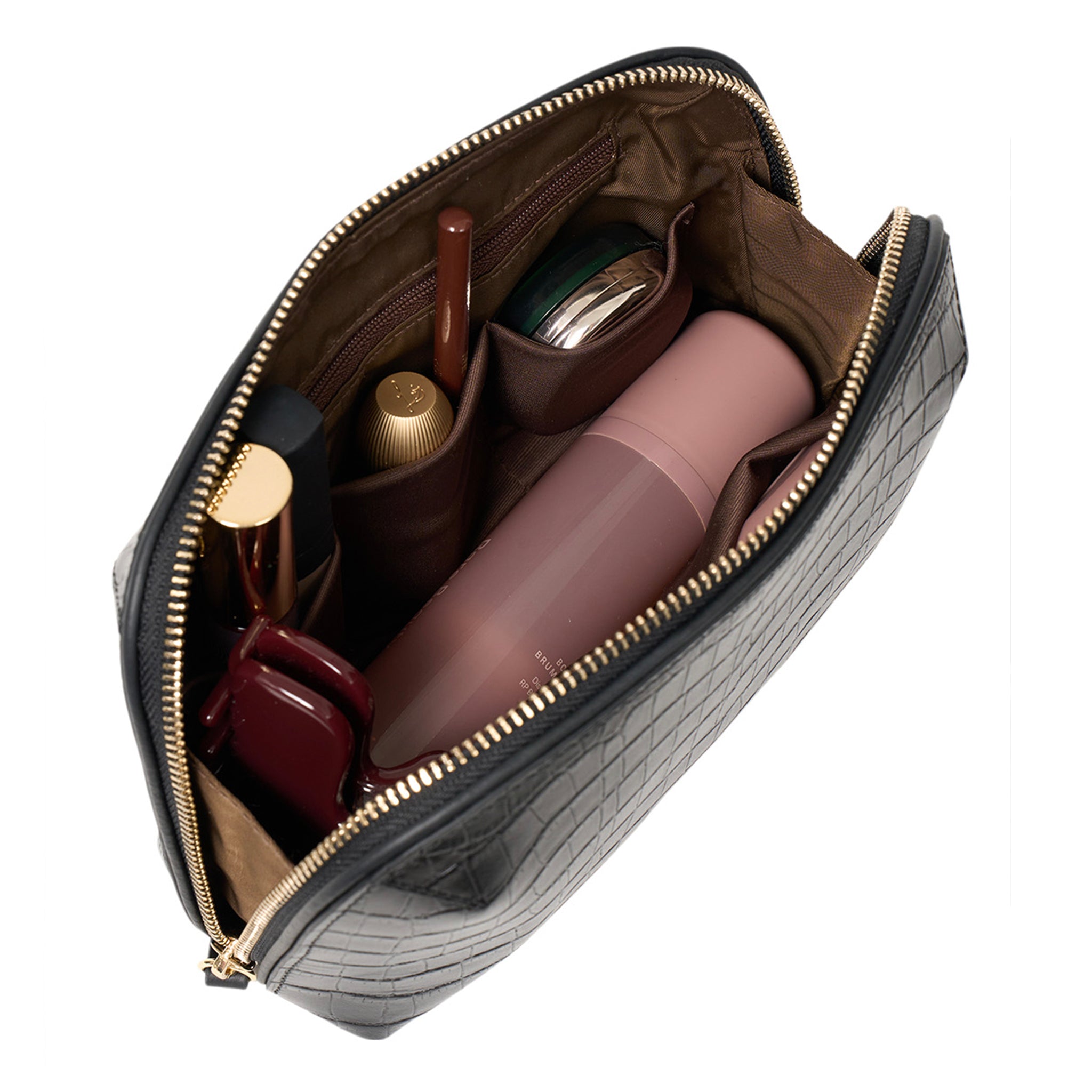 Open gray crocodile-patterned handbag with various items including a pink bottle and gold accents.