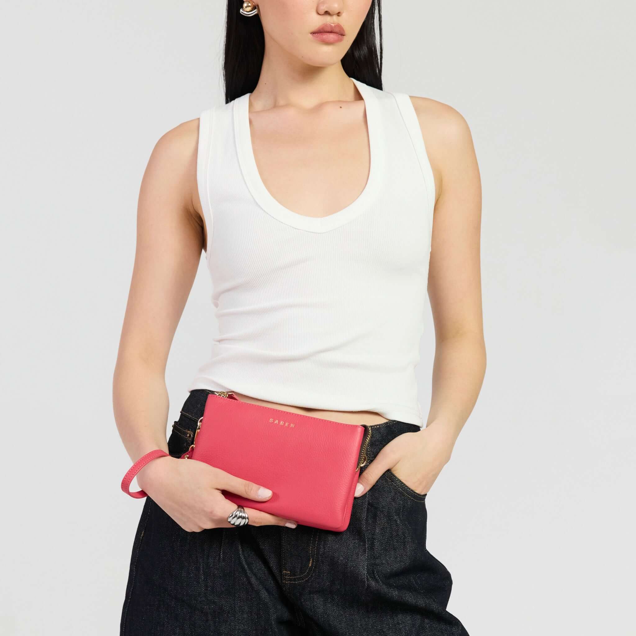 Saben Tilly Crossbody Bag - Azalea held by model in white top and denim pants.