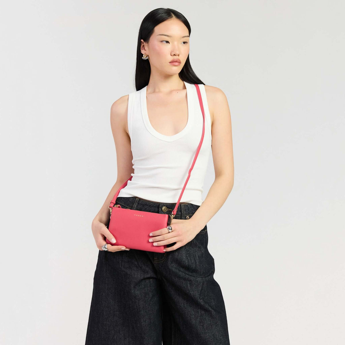 Saben Tilly Crossbody Bag - Azalea showcased by a model in a white top and denim trousers.