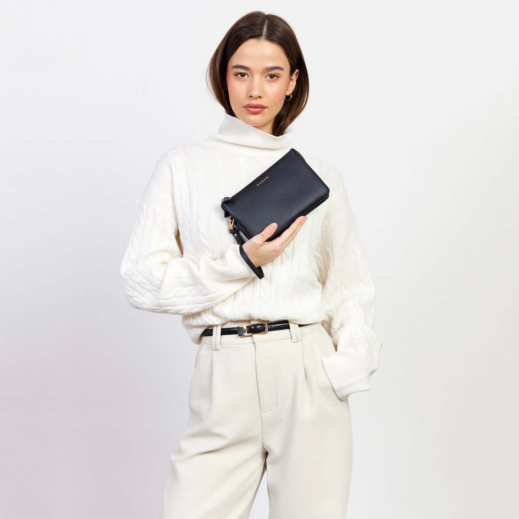Alt Tag: Model holding Saben Tilly Crossbody Bag - Black leather clutch wallet with wrist strap