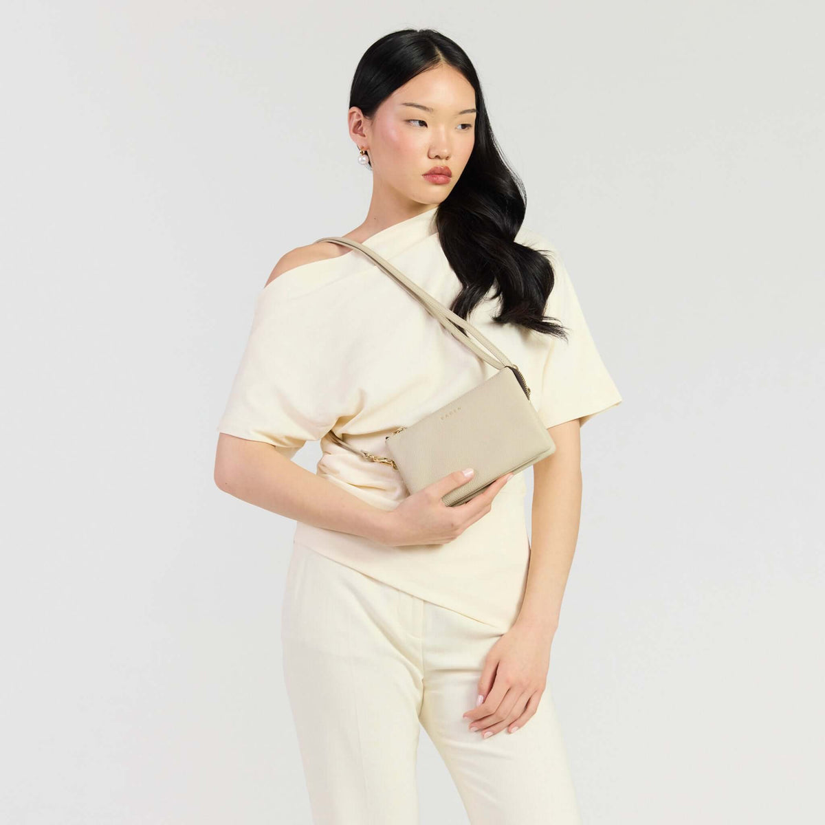 Saben Tilly Crossbody Bag - Oyster being held by a model, showcasing its stylish and versatile design.