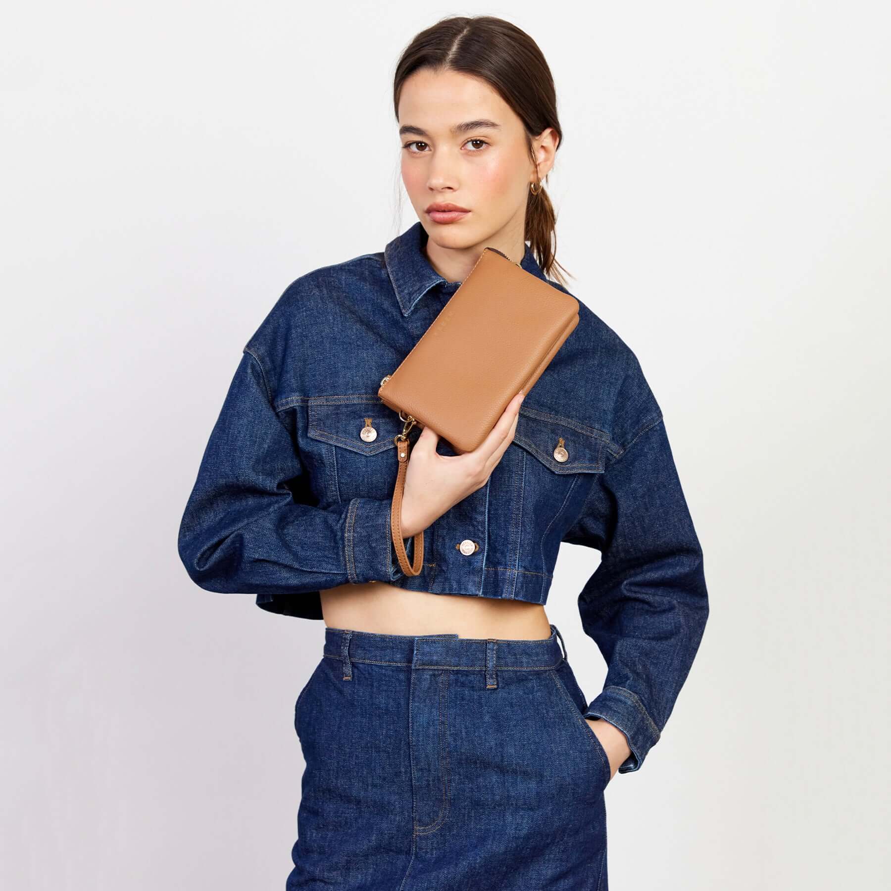 Alt Tag: Model holding Saben Tilly Crossbody Bag - Toffee toffee leather wallet clutch and crossbody with wrist strap