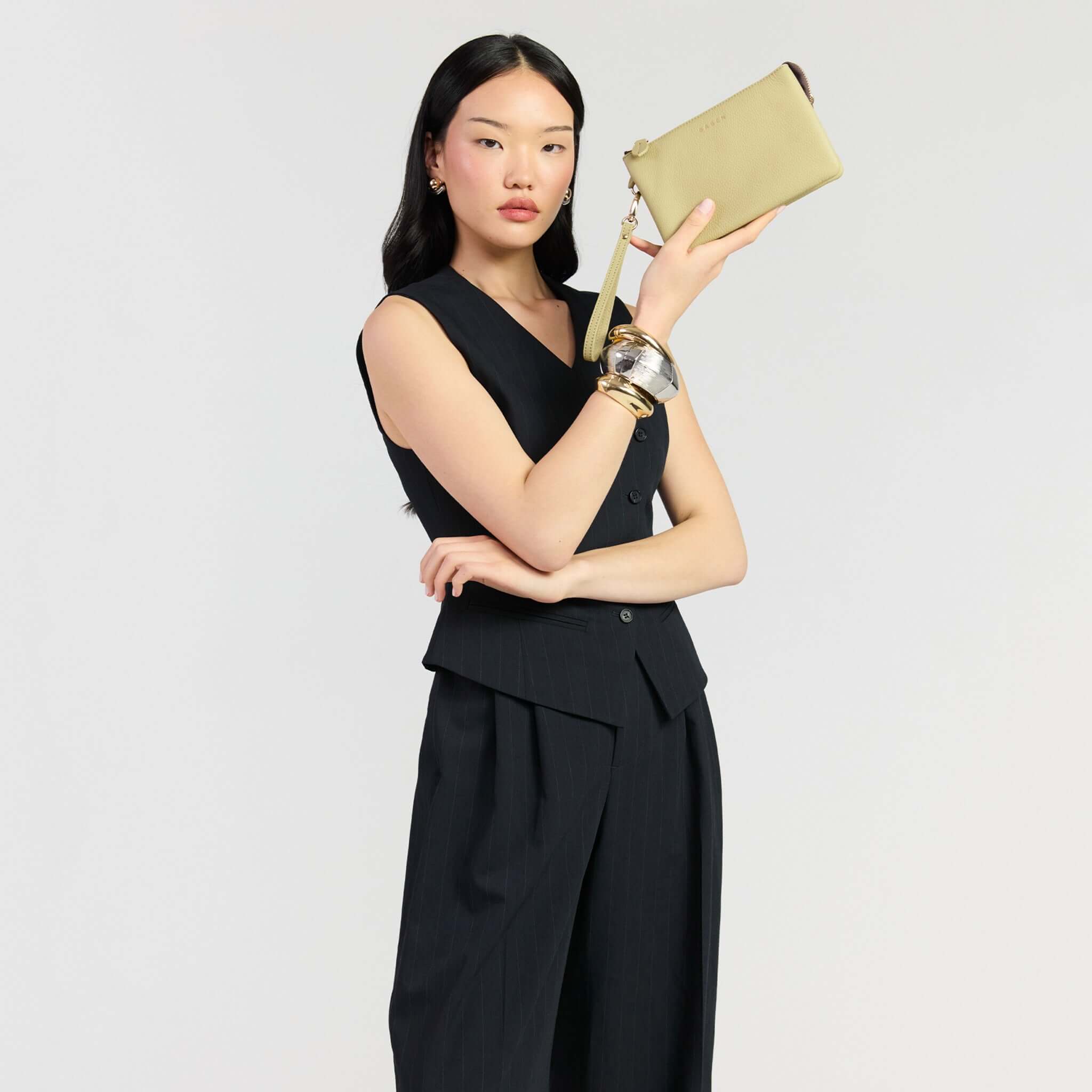 Saben Tilly Crossbody Bag - Willow held by a model wearing a stylish black outfit, showcasing its versatility.
