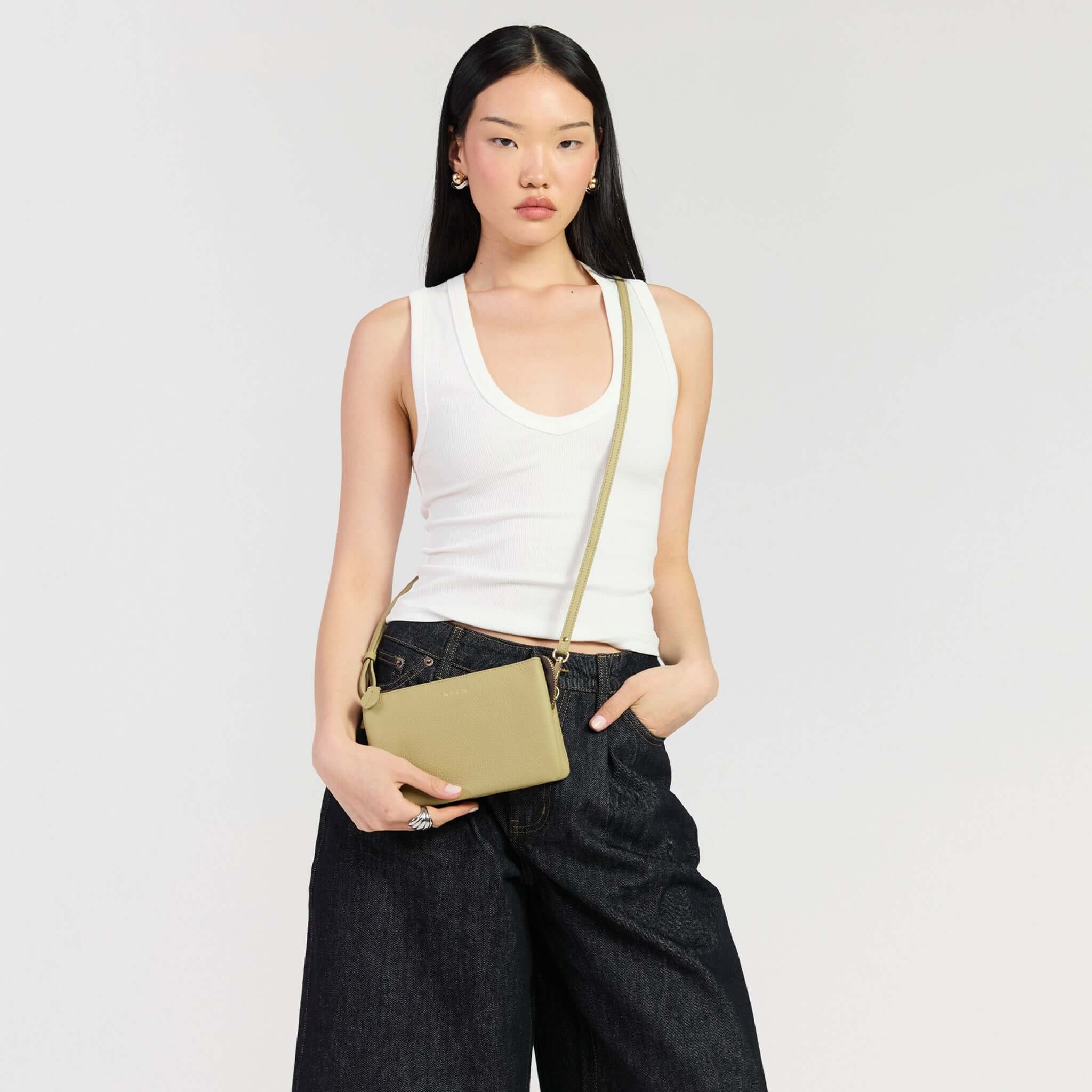 Saben Tilly Crossbody Bag - Willow showcased by model in white tank and dark jeans.