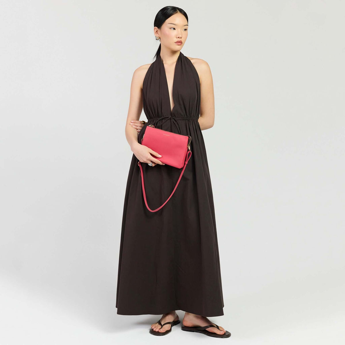 Saben Tilly's Big Sis Crossbody Bag - Azalea held by a model in a black halter dress.
