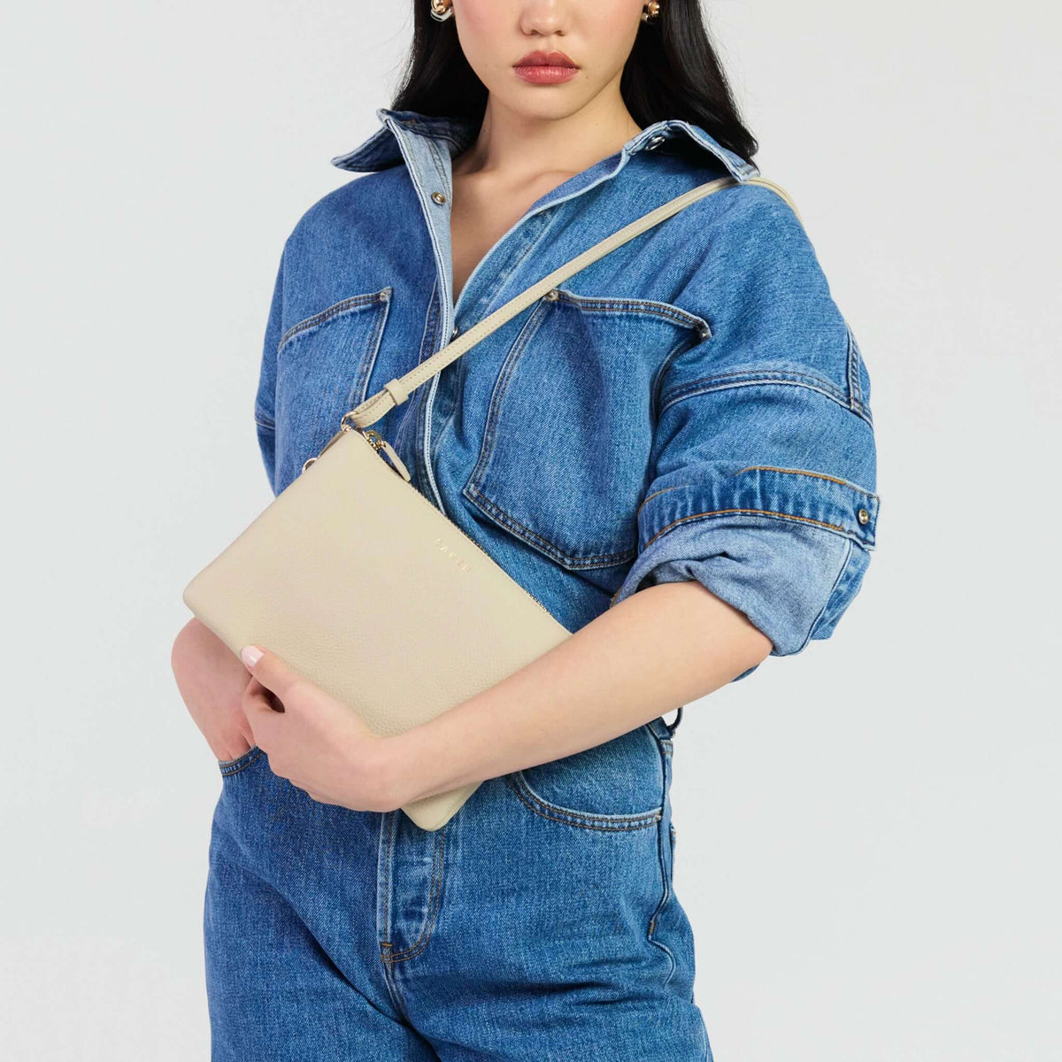 Saben Tilly's Big Sis Crossbody Bag - Oyster being held by a model in denim attire.