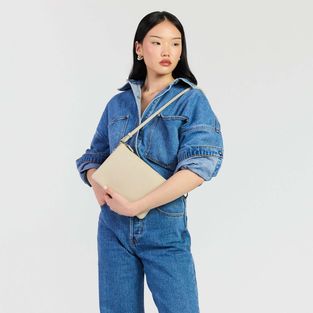 Saben Tilly's Big Sis Crossbody Bag - Oyster being carried by a model in denim attire.