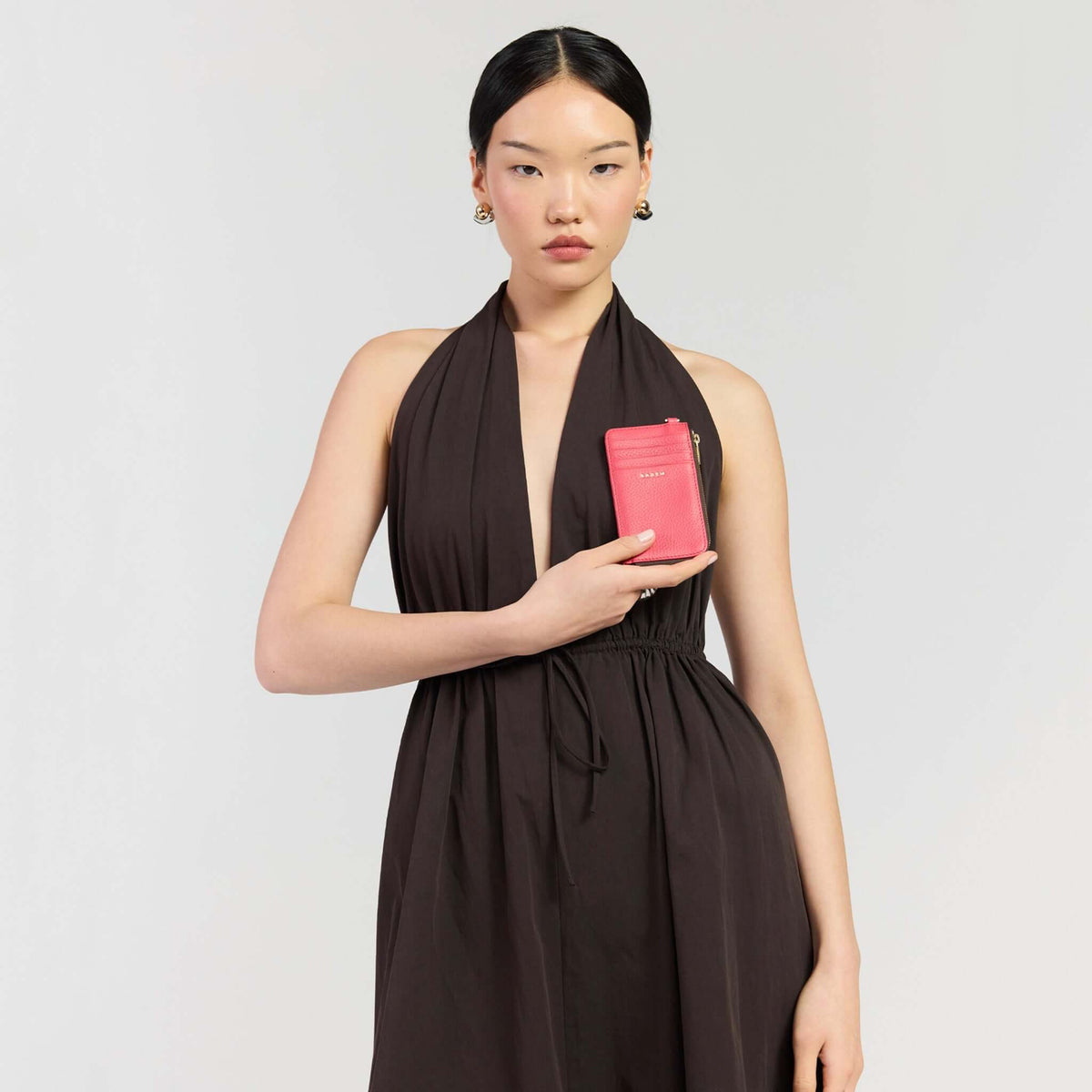 Saben Winona Card Holder - Azalea held by a model wearing a halter dress, showcasing its stylish design in a vibrant hue.