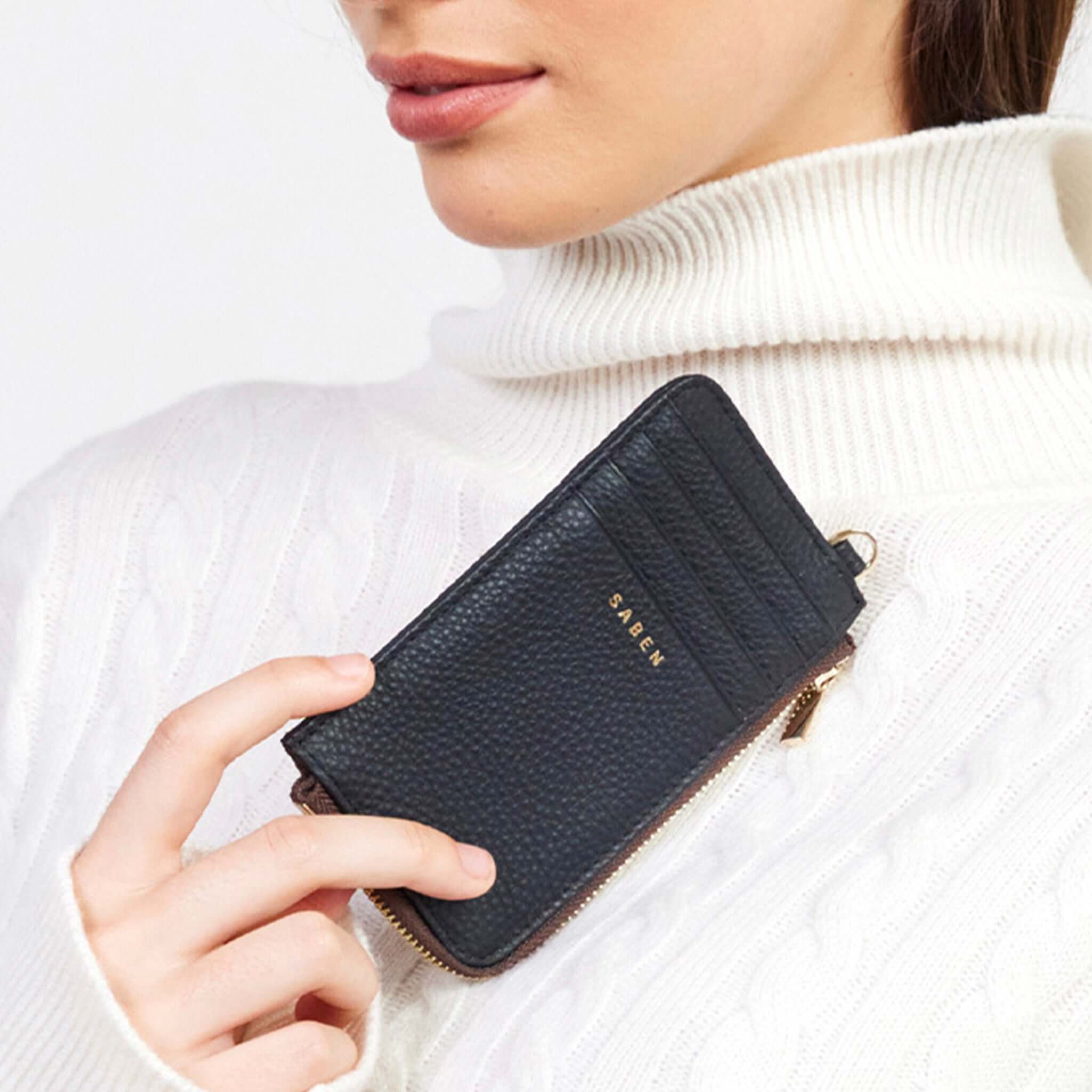 Alt Tag: Saben Winona Card Holder - Black textured leather zip card holder held by model, compact wallet with 8 card slots