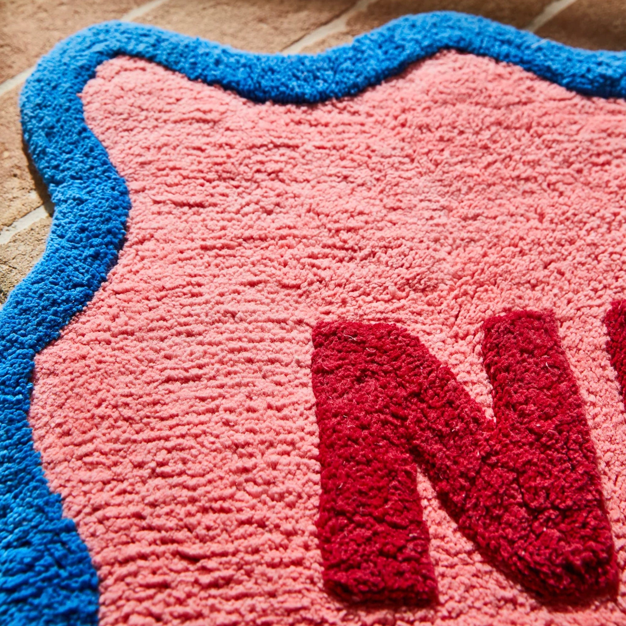 Pink and blue rug with a red letter 'N'