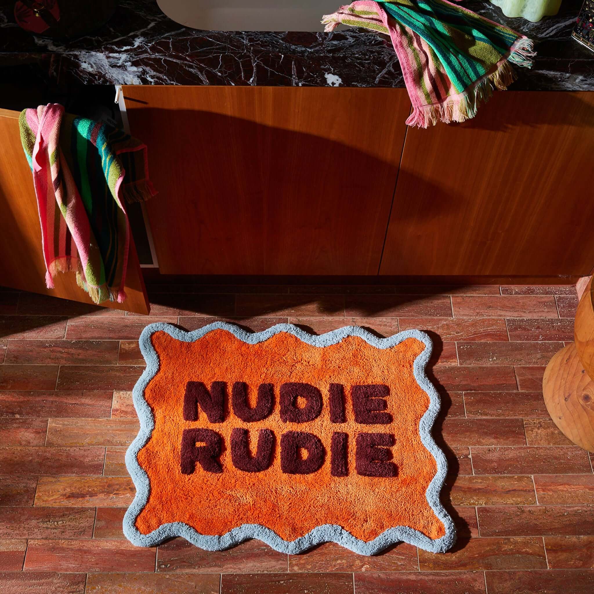 Sage x Clare Amalie Nudie Bath Mat - Orangerie displayed in a stylish bathroom setting with vibrant colors.